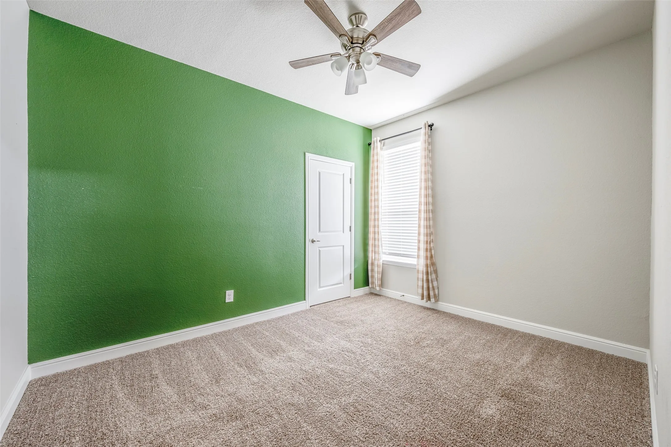 Bright bedroom featuring fresh green accent wall, neutral complementary wall finishes, and neutral-tone carpet flooring