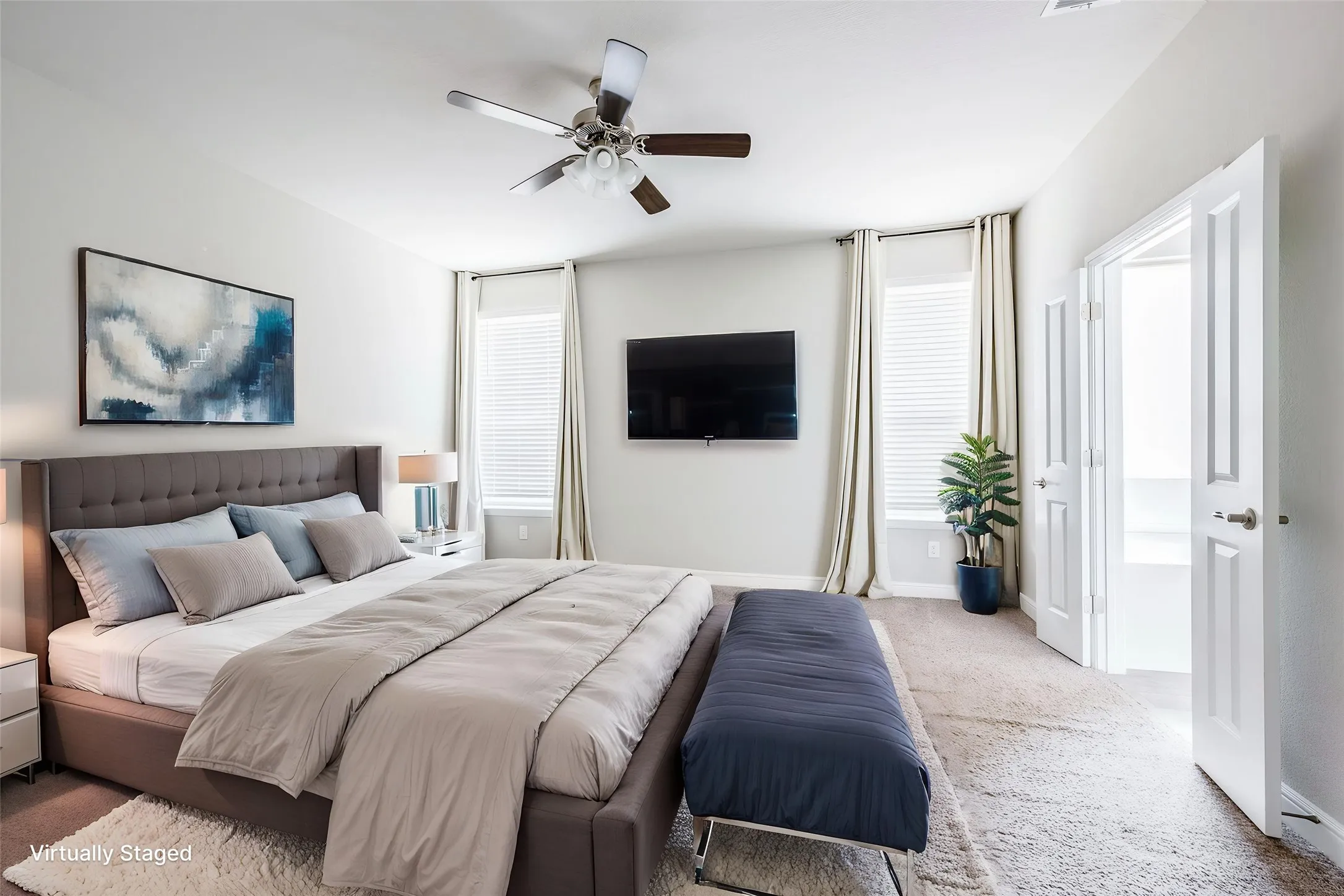 Wall-mounted television, ceiling fan with light fixture, window with blinds and drapes, and double doors