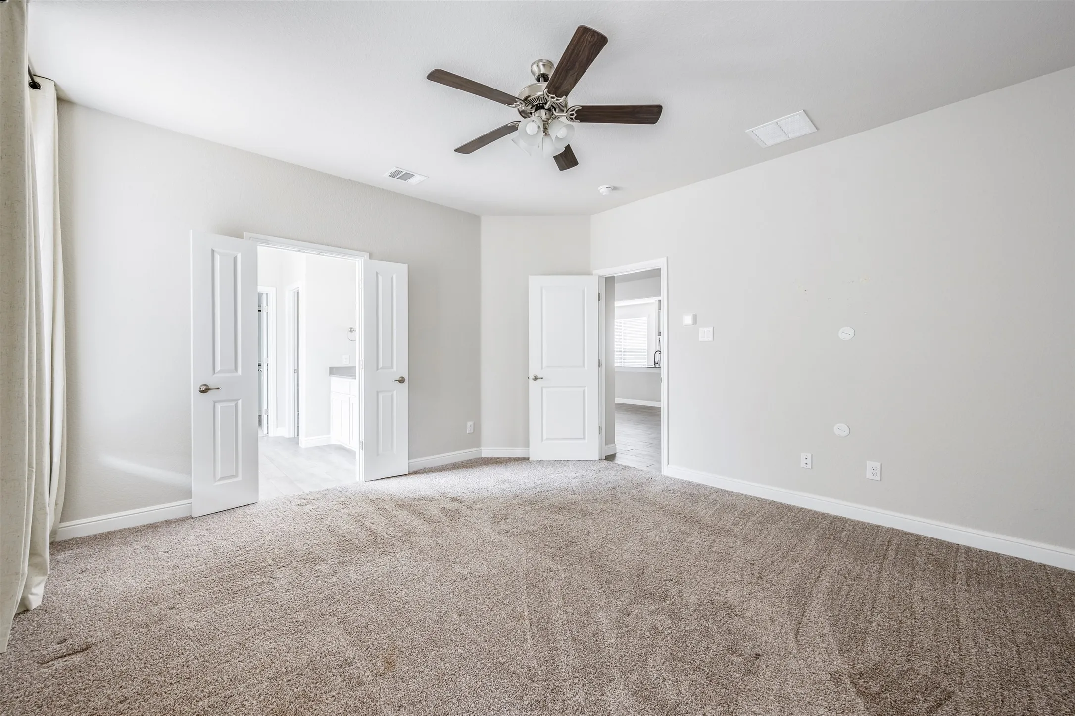 Neutral tone walls, ceiling fan with wood-finish blades, carpeted flooring, and white paneled doors