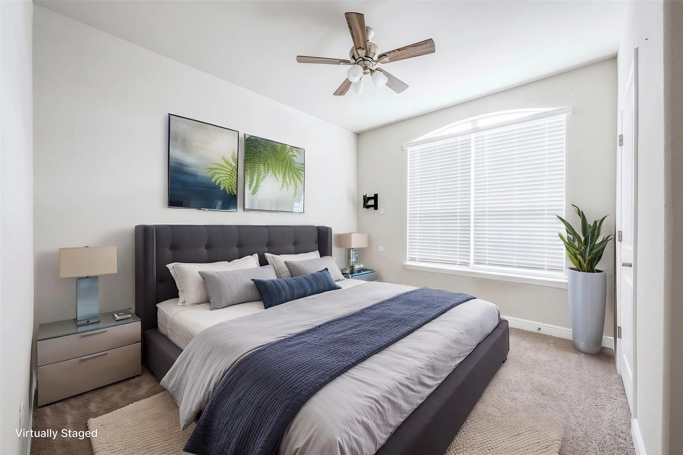 Arched window with blinds, ceiling fan, and carpeted flooring