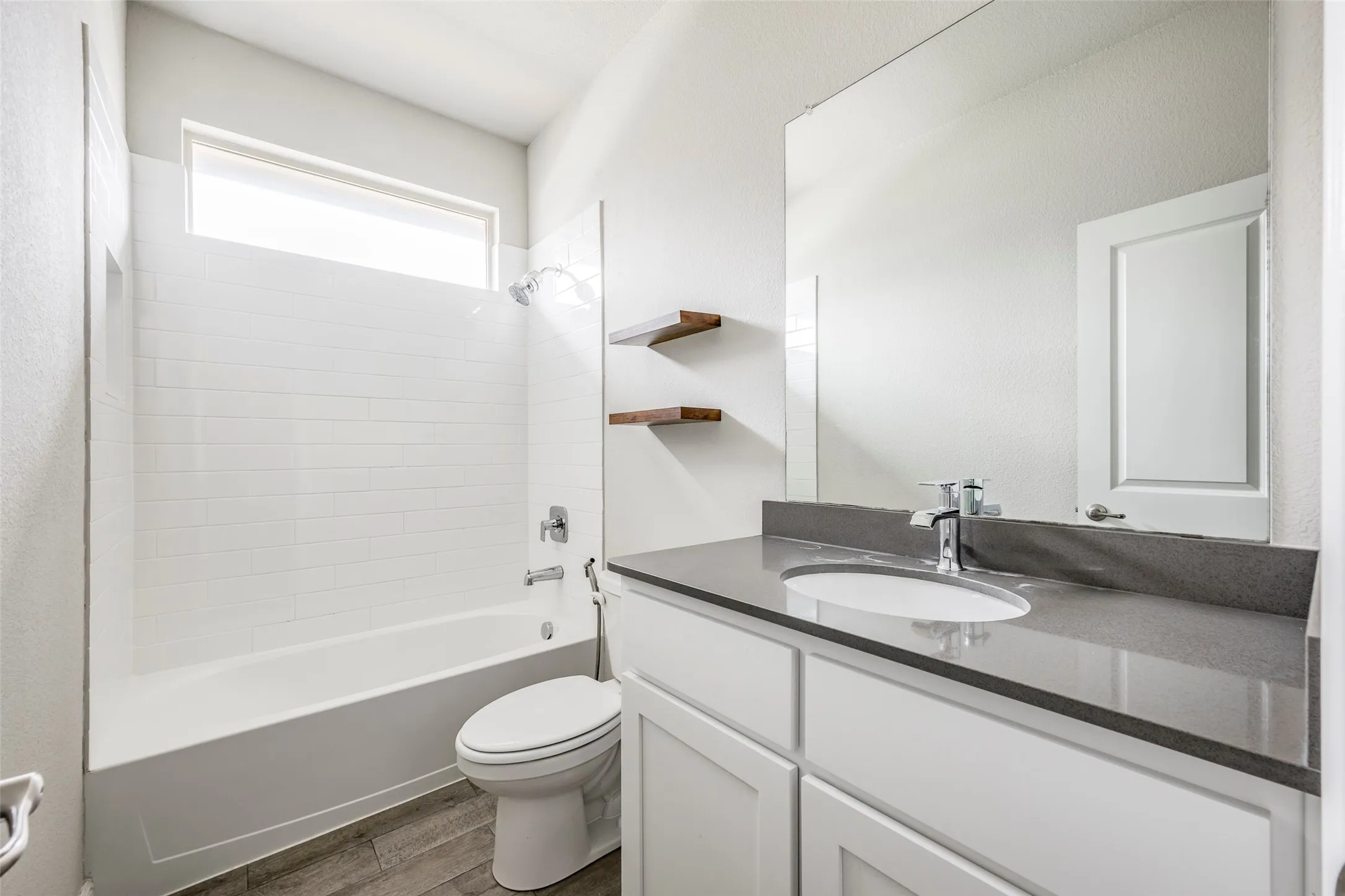 Modern bathroom featuring a white vanity with dual drawers, dark quartz countertop, and an undermount sink with chrome faucet