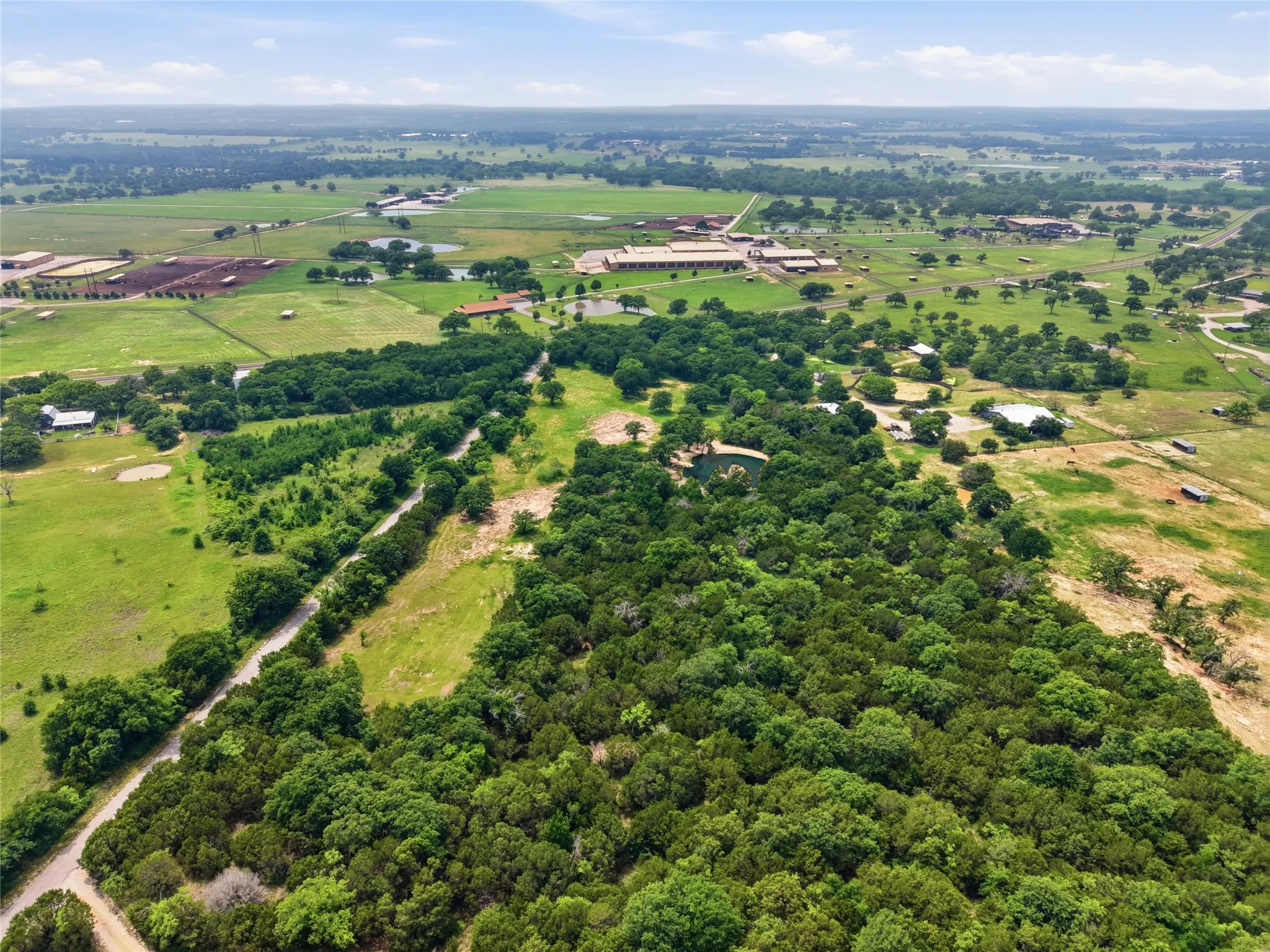 Expansive rural landscape featuring lush green fields and dense tree coverage