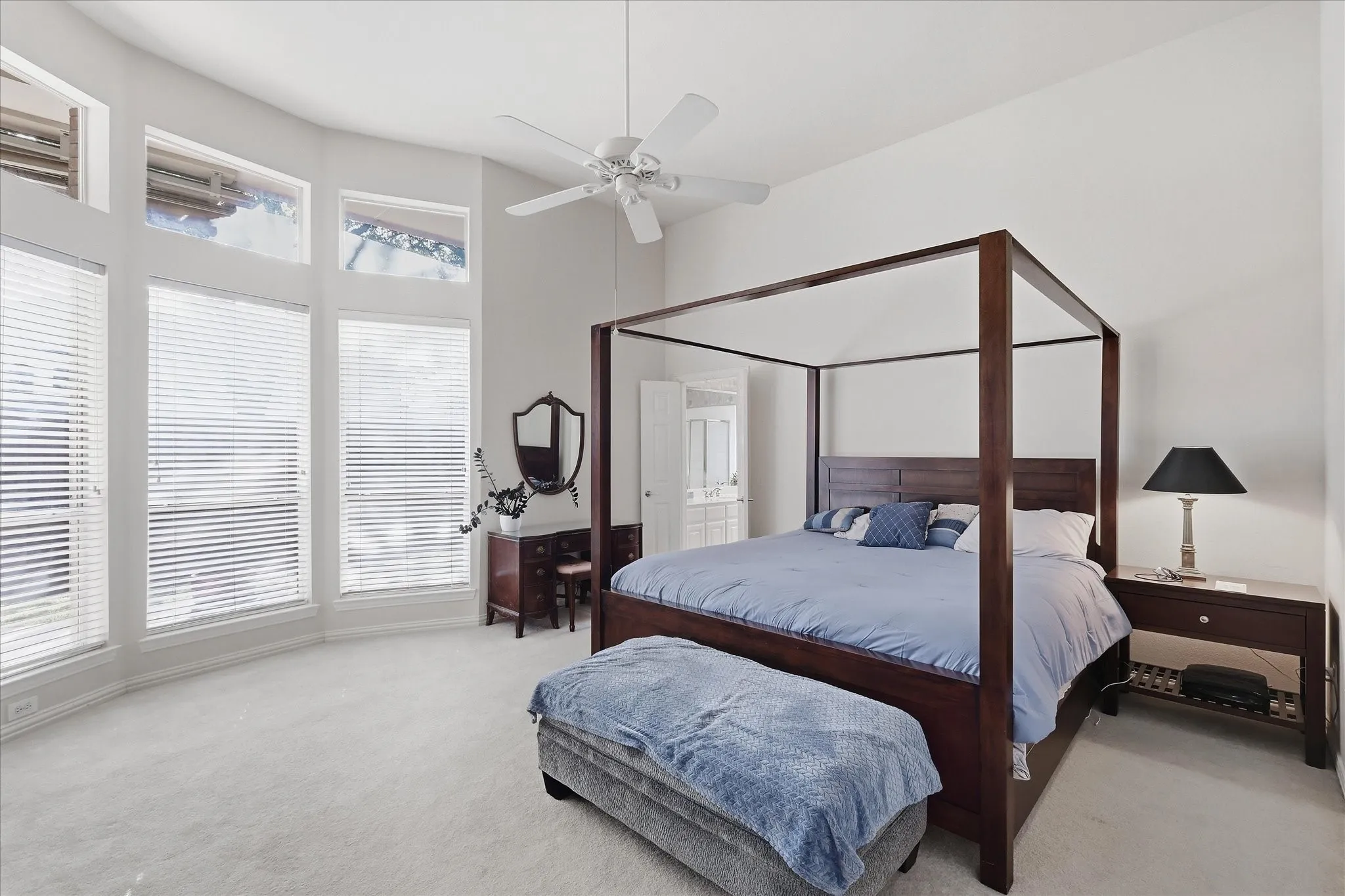 Chef's kitchen featuring black cabinetry with raised-panel doors, granite countertops, a large center island with black surface, stainless steel appliances including a dishwasher and refrigerator, pendant lighting over the workspace, and abundant natural light from multiple windows
