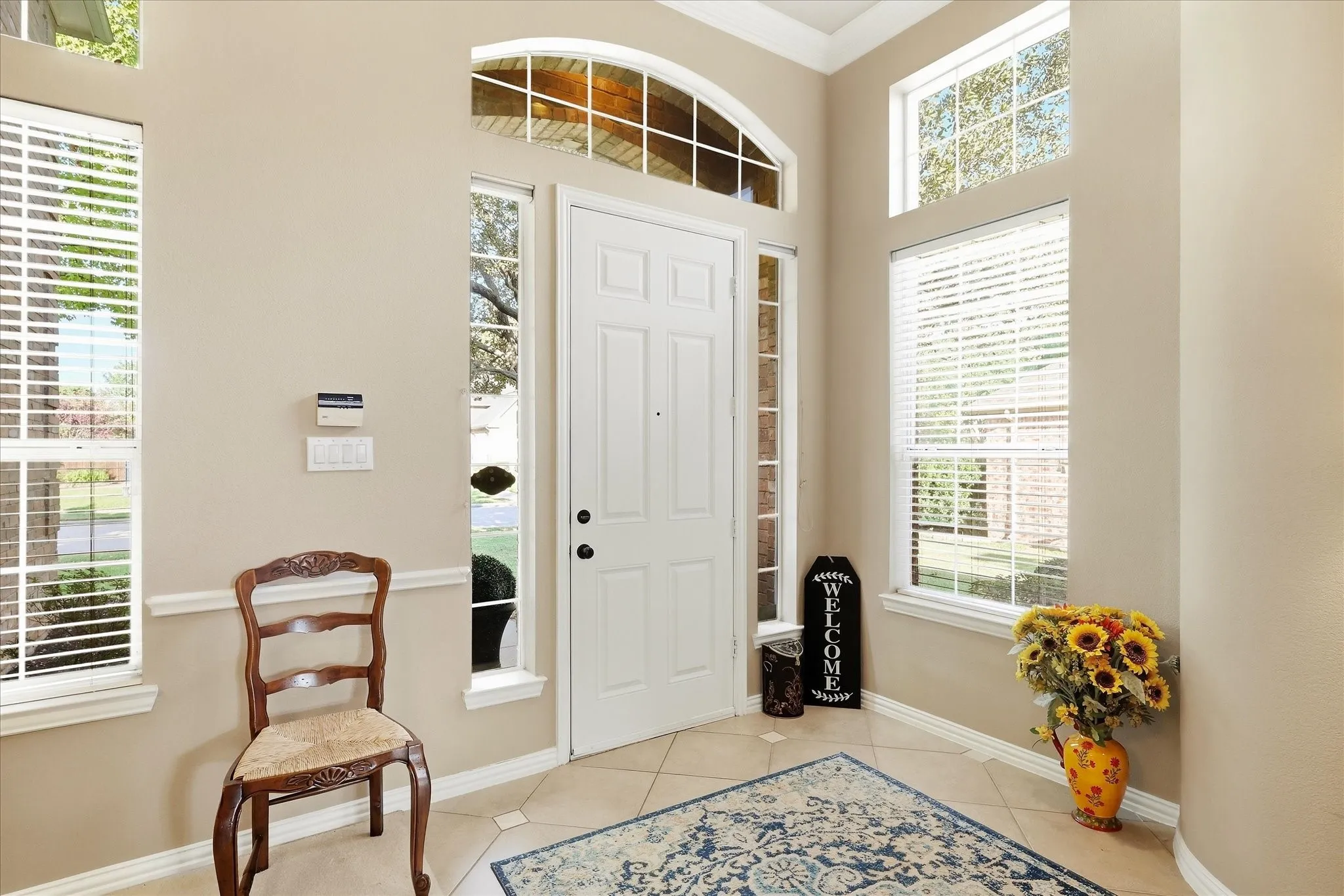 Foyer featuring a paneled door, arched transom window, side light windows, and ceramic tile flooring with decorative inserts