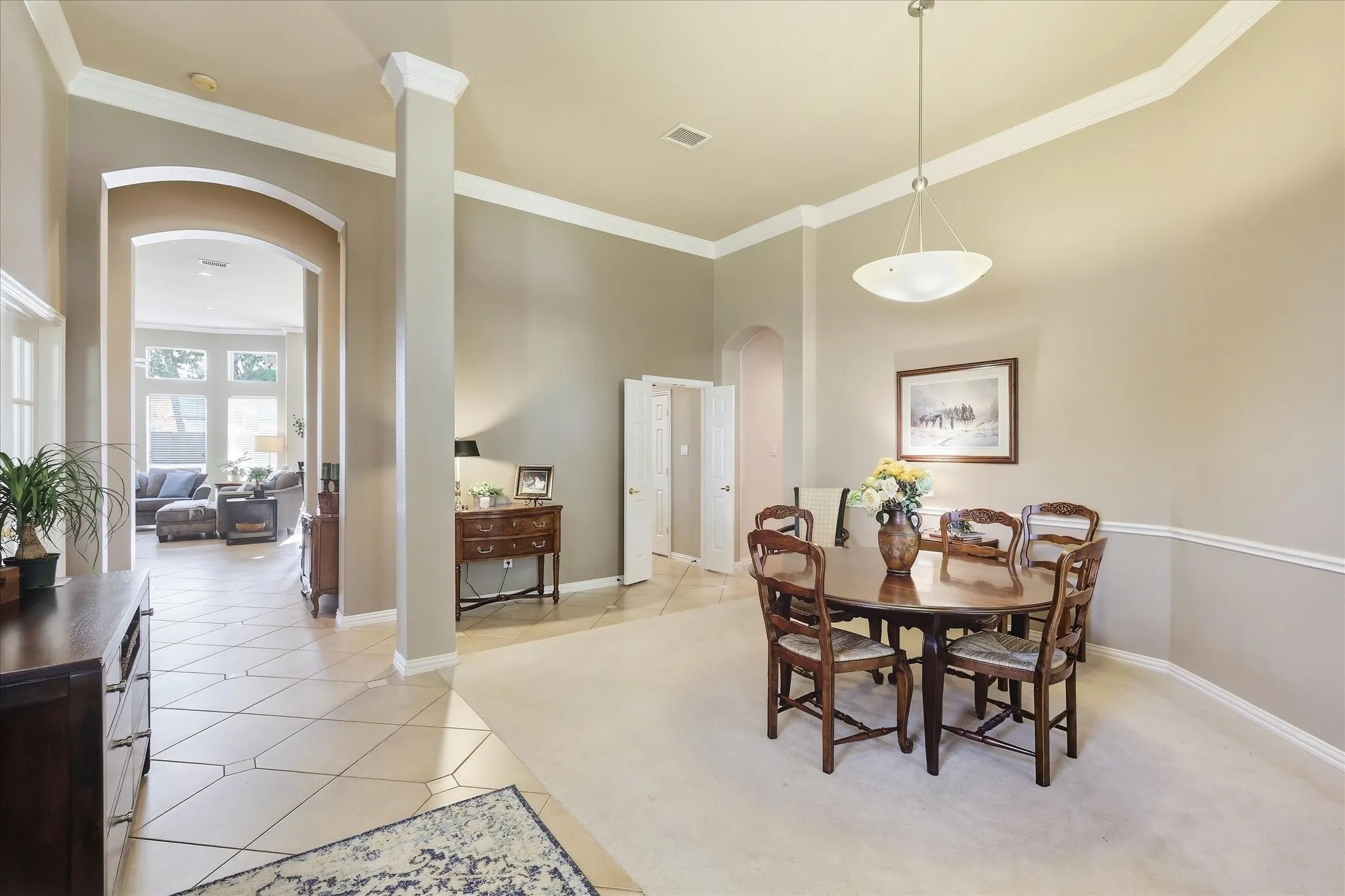 Carpeted dining area with a contemporary pendant light fixture, wainscoting, and crown molding