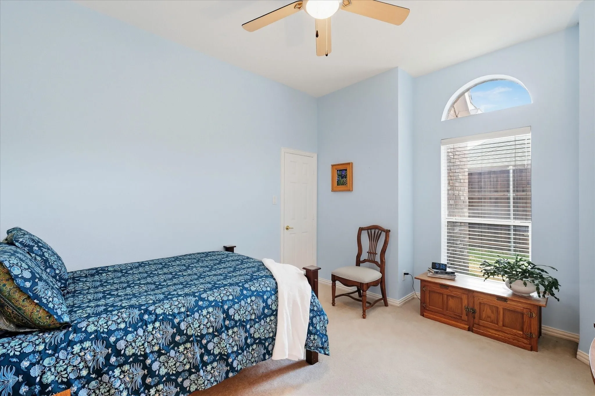 Vaulted ceiling with a ceiling fan, carpet flooring, and a doorway leading to an adjacent space with tile flooring