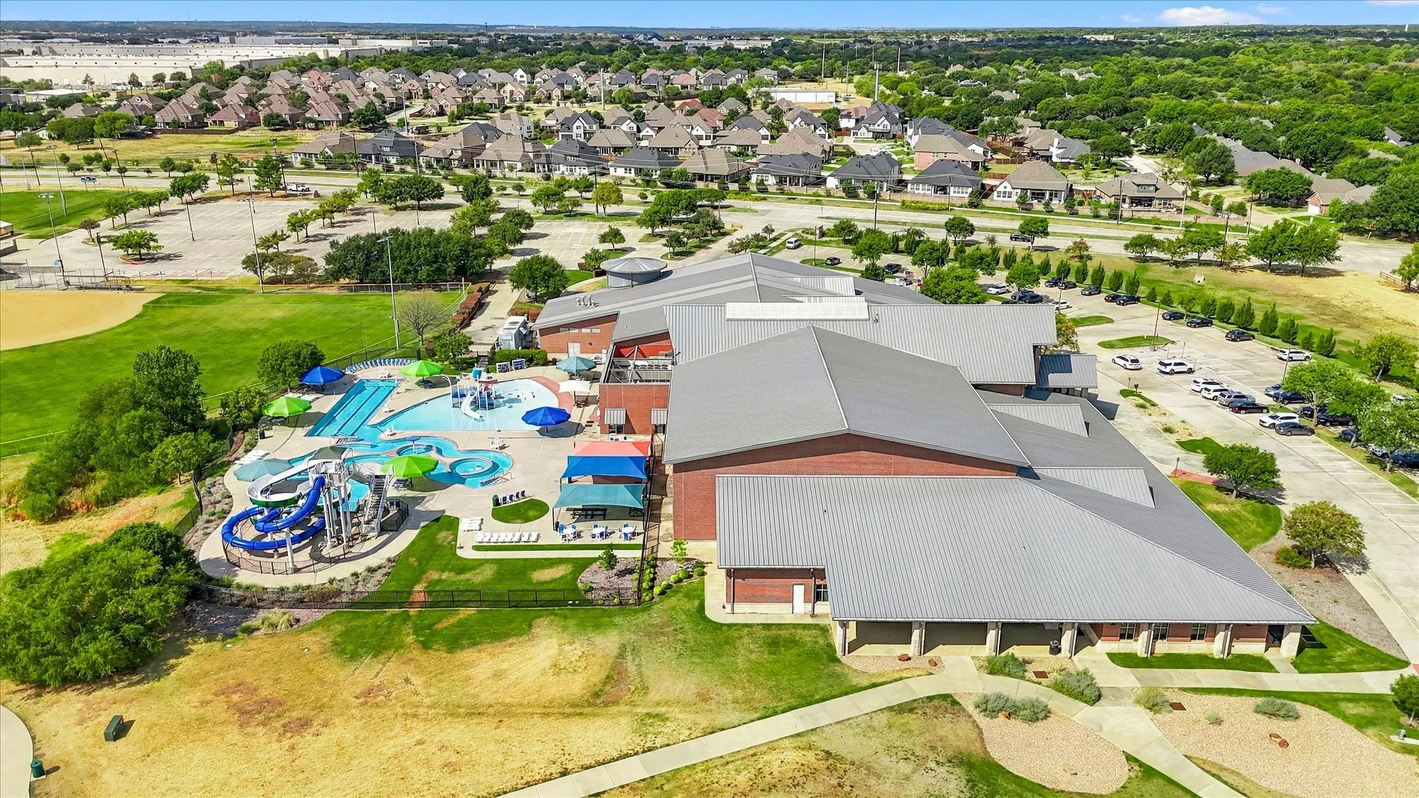 Expansive community complex featuring a water park with multiple slides, a large swimming pool, and a baseball field