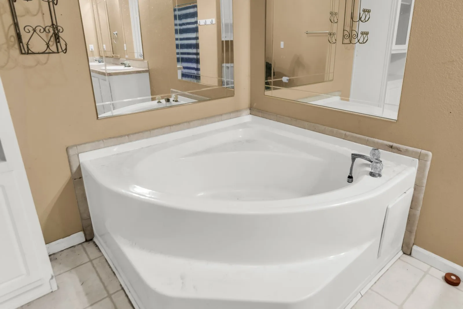 Corner soaking tub with a deck-mounted faucet and tiled surround