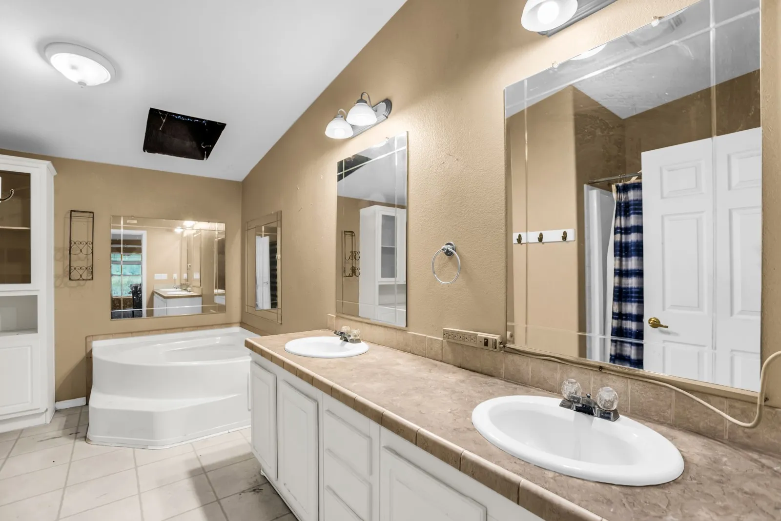 Dual vanity with integrated sinks, spacious corner soaking tub, and tile flooring