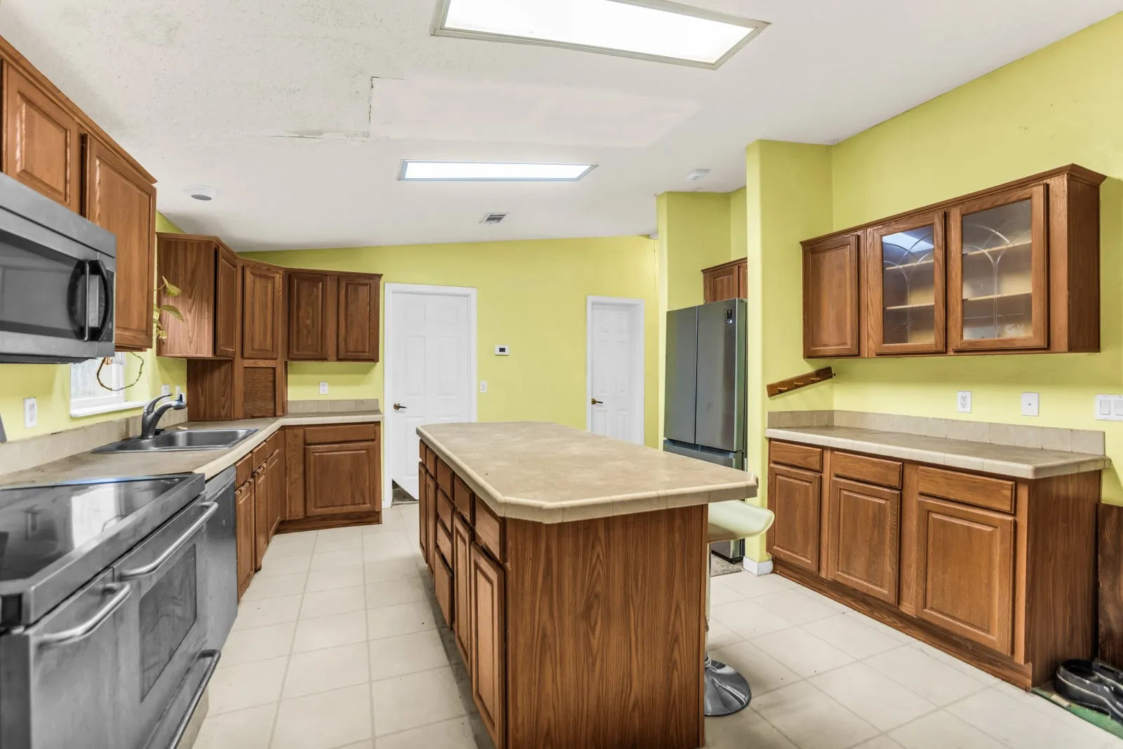 Kitchen featuring a central island, wood cabinetry, stainless steel appliances, and tile flooring