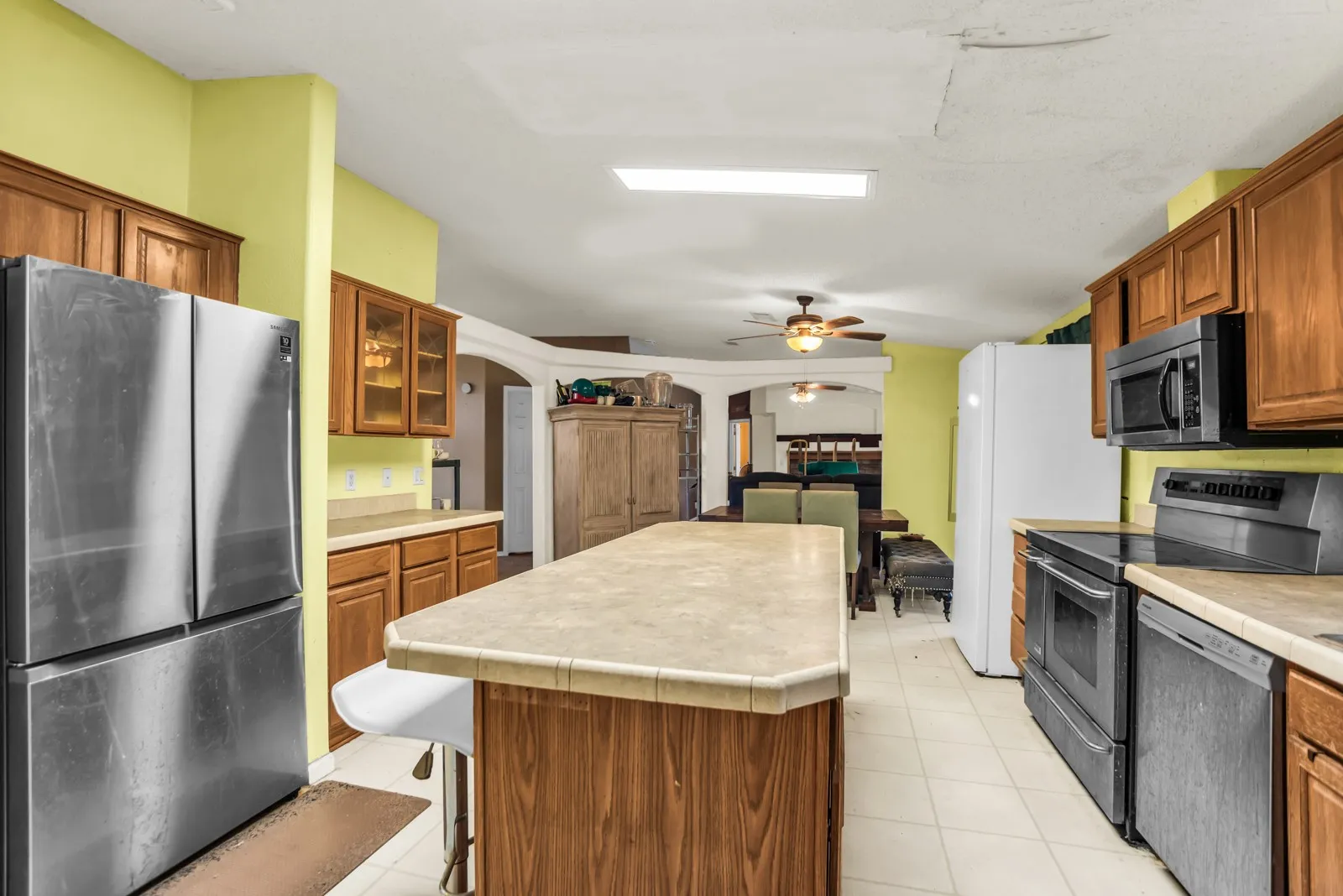 Wood-finish cabinetry, tile flooring, and a kitchen island with a tile countertop