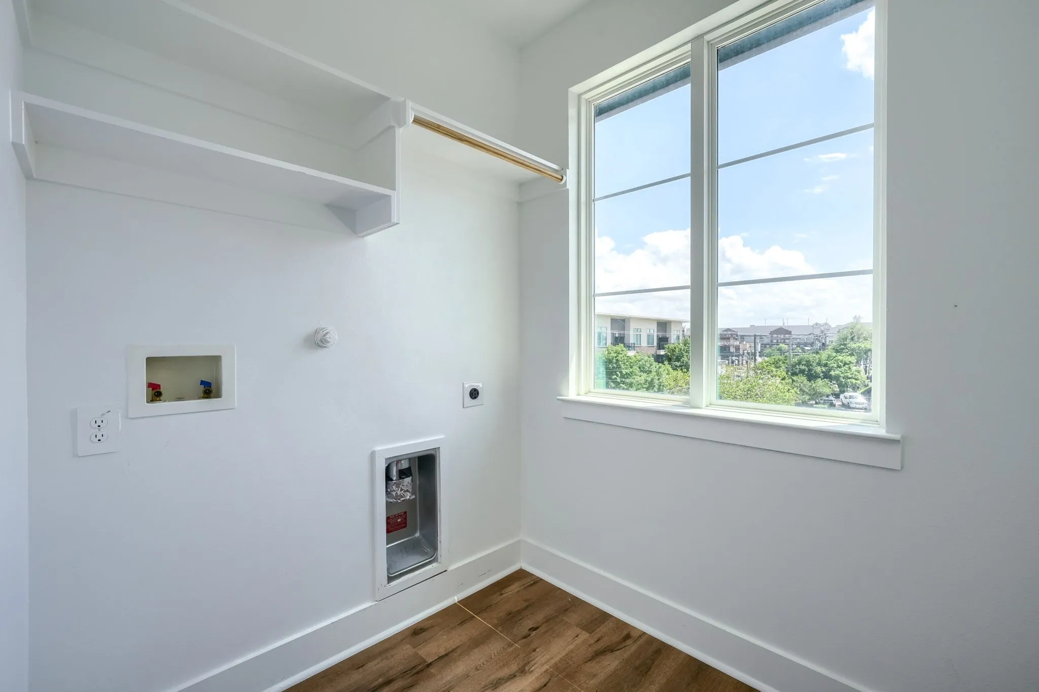 Bright utility space featuring wood-finish flooring, a large window, and built-in shelving