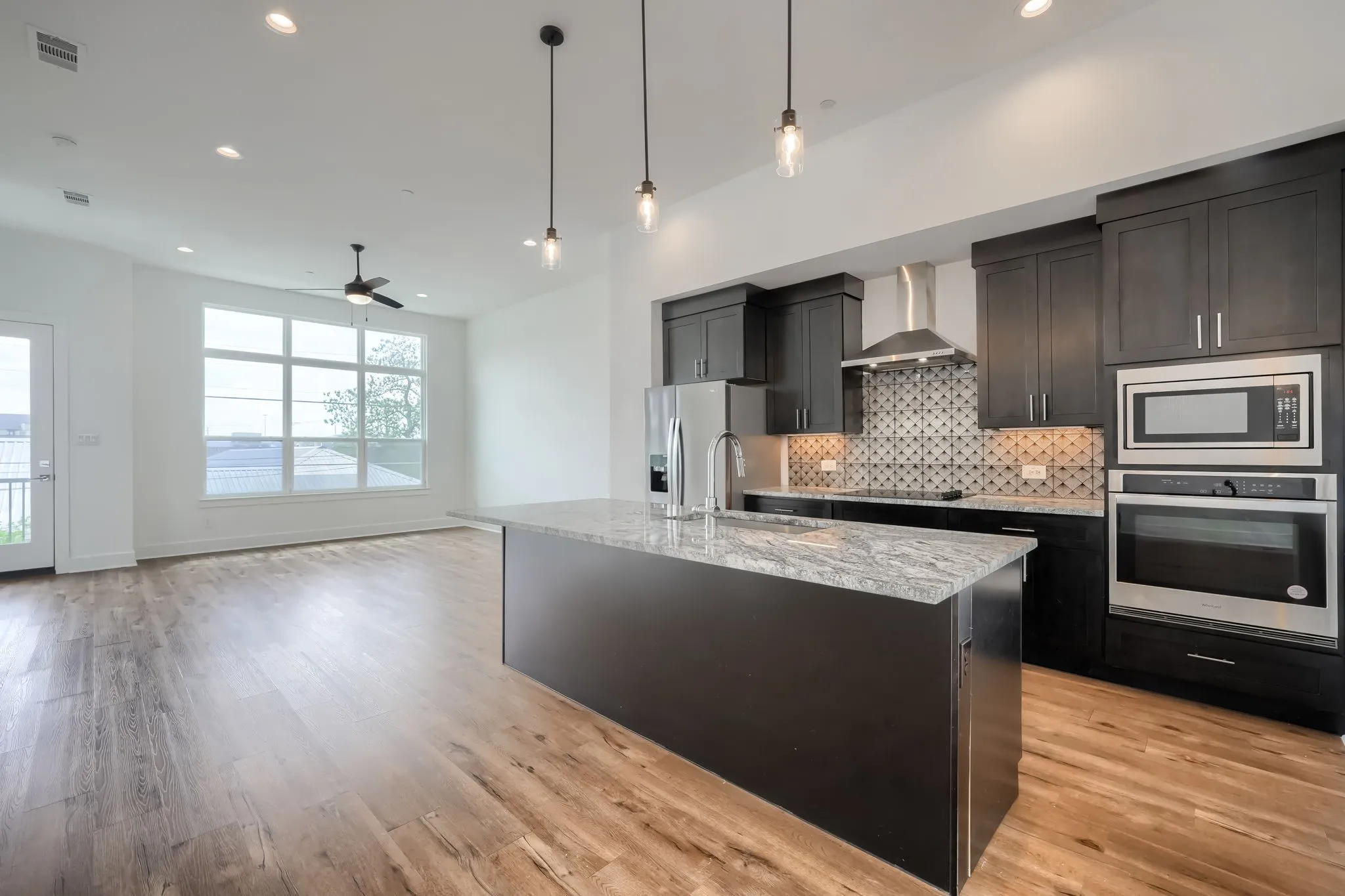 Open-concept kitchen and living area featuring wood-finish flooring, recessed lighting, and a ceiling fan