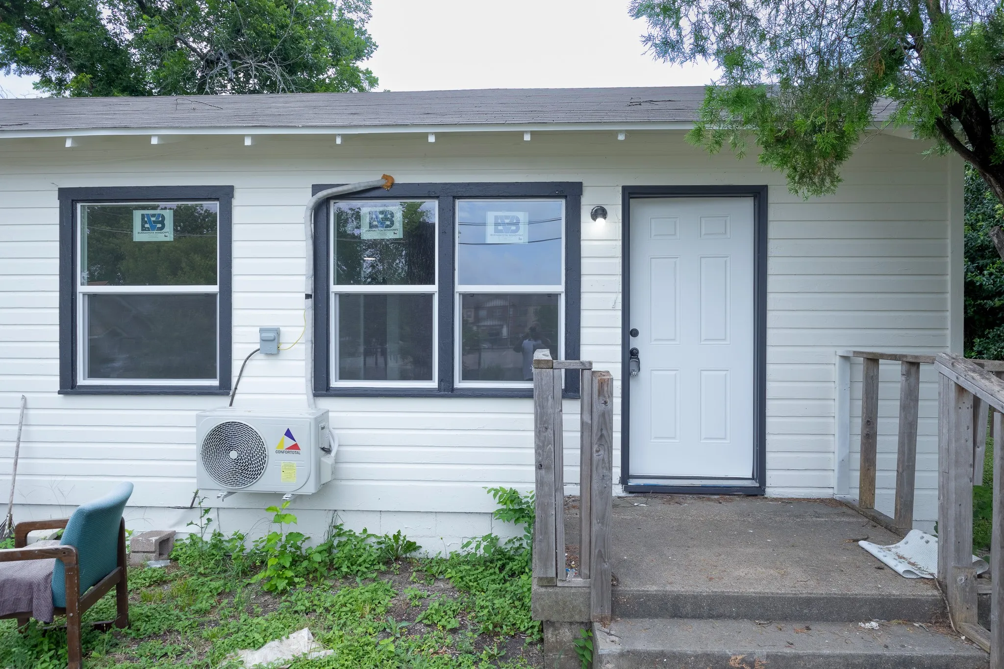 White paneled siding exterior with dark trim windows and a white paneled door
