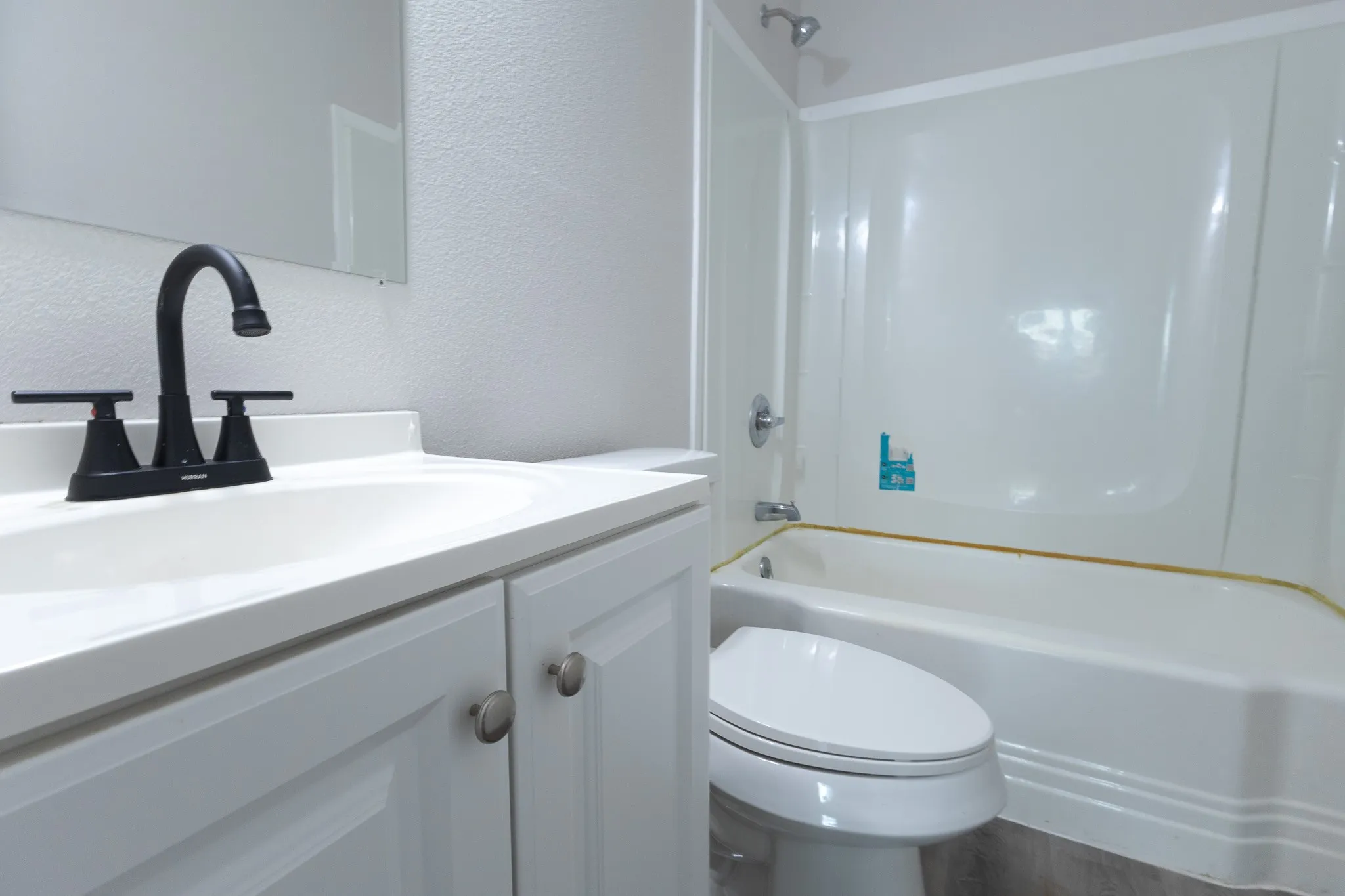 White vanity with shaker-style cabinetry, matte black faucet, and integrated sink