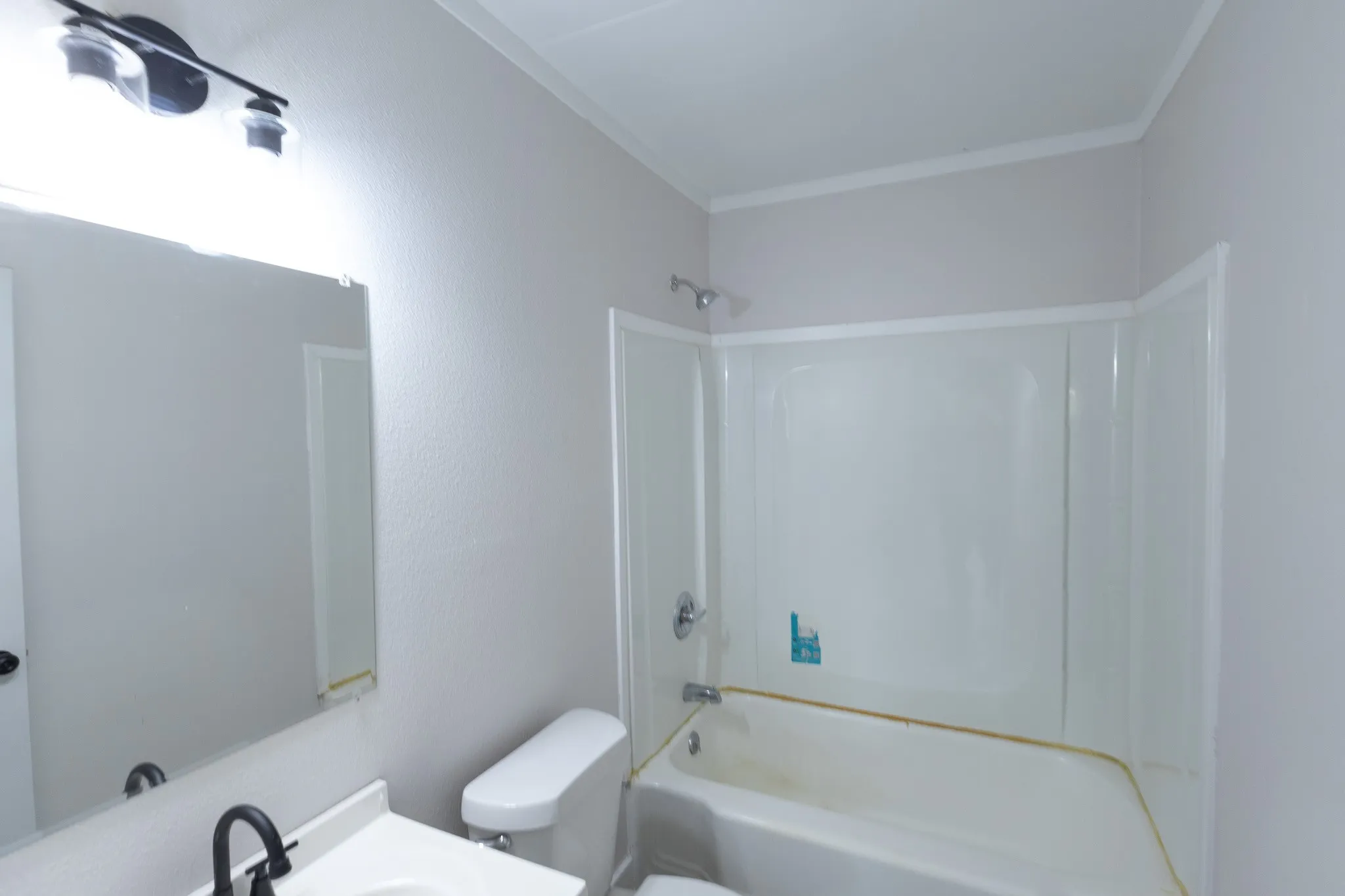 Built-in tub with integrated shower, vanity with an integrated sink, and a wall-mounted mirror