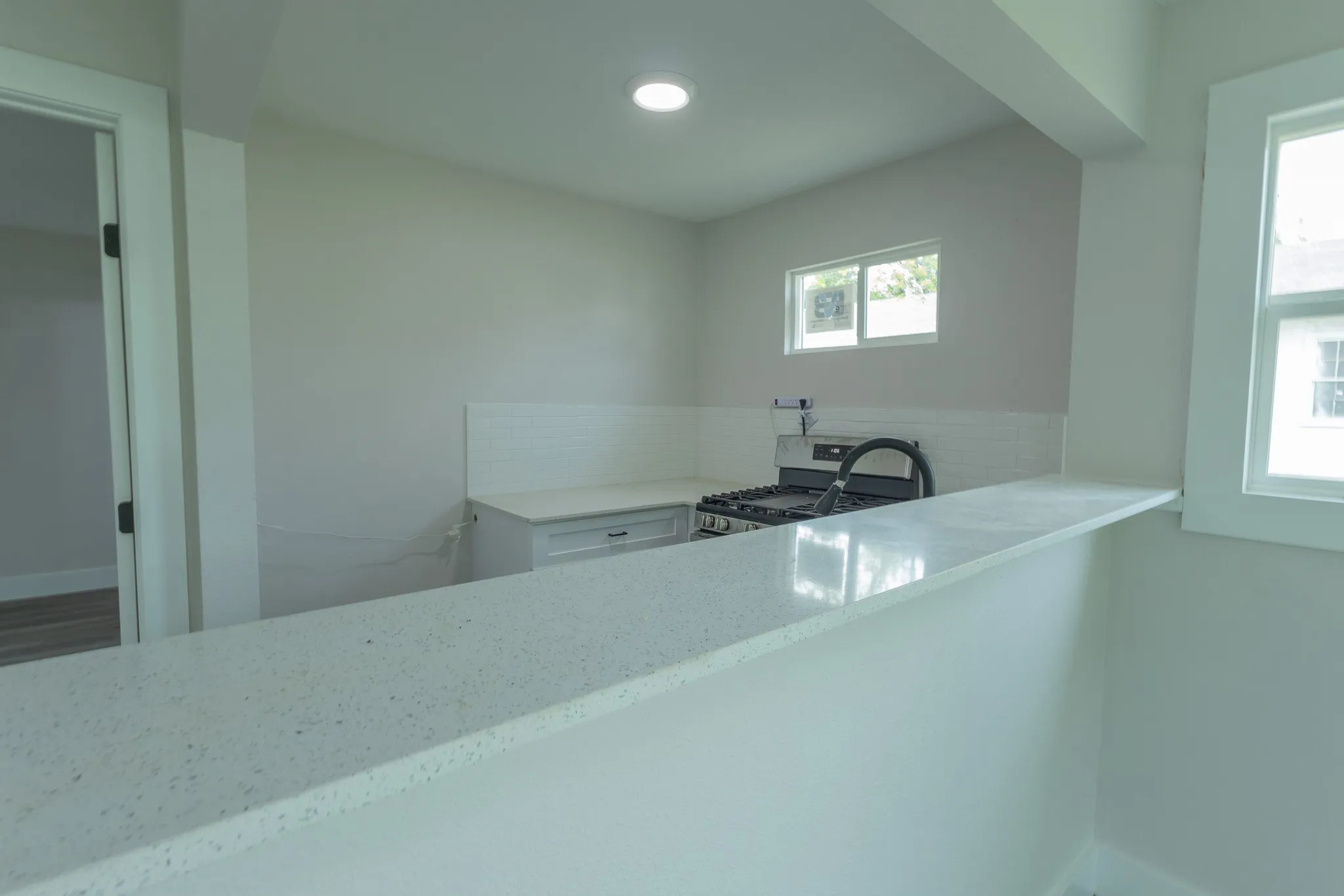 Kitchen featuring a gas range, subway tile backsplash, white cabinetry, and light-toned countertops