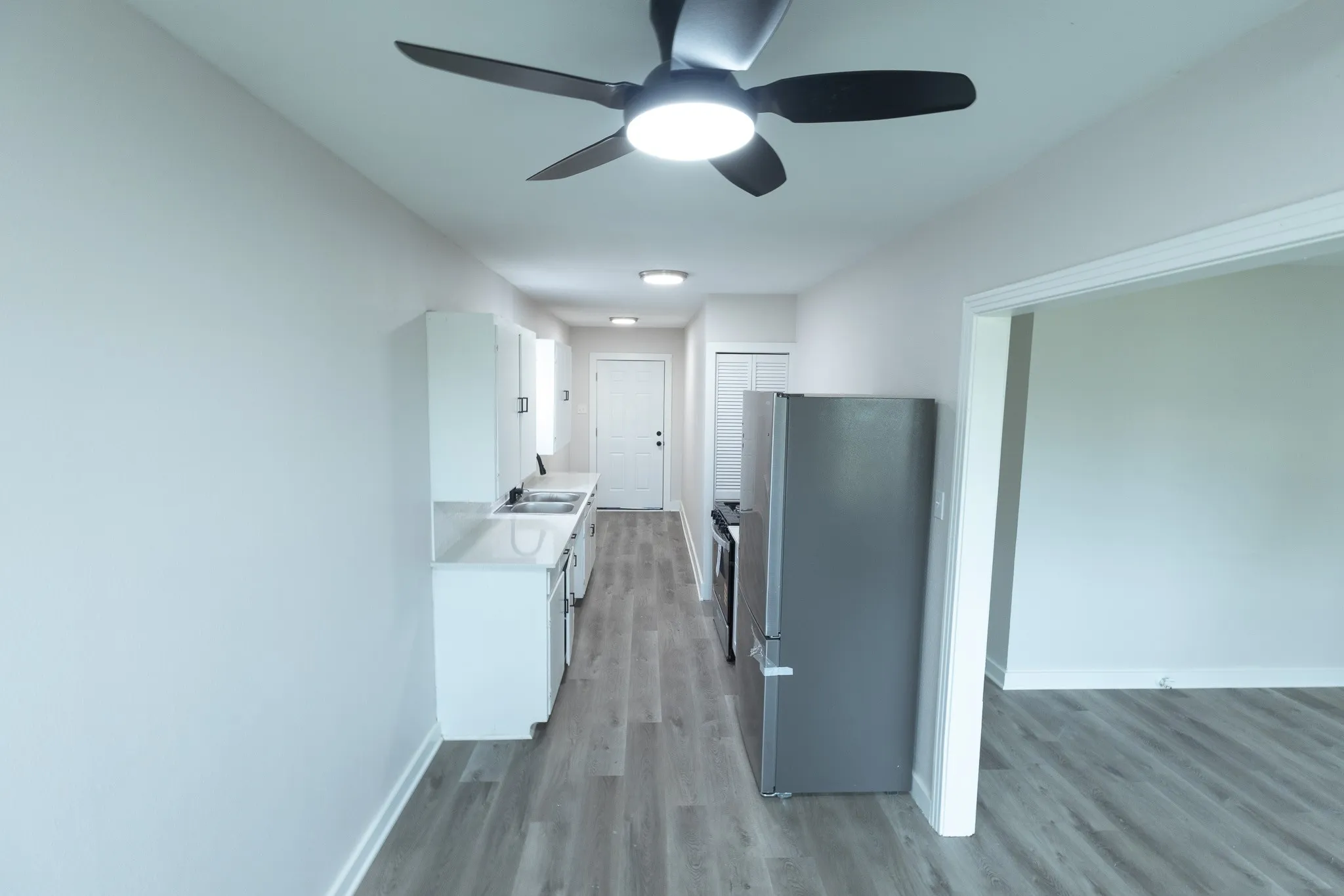 Kitchen featuring a ceiling fan with integrated lighting, recessed lighting, white cabinetry, integrated sink, and stainless steel appliances
