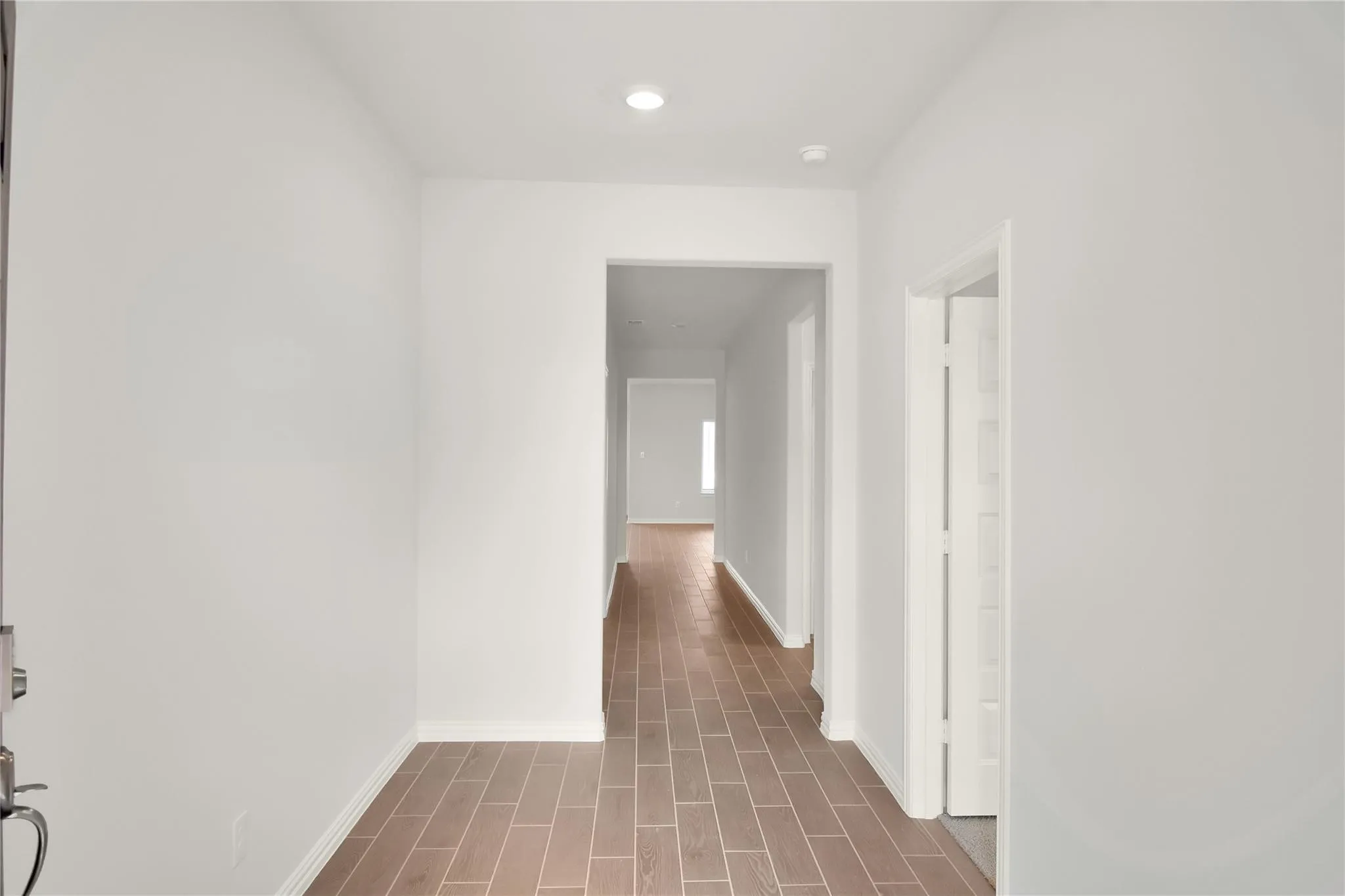 Recessed lighting illuminates the hallway with wood-finish flooring