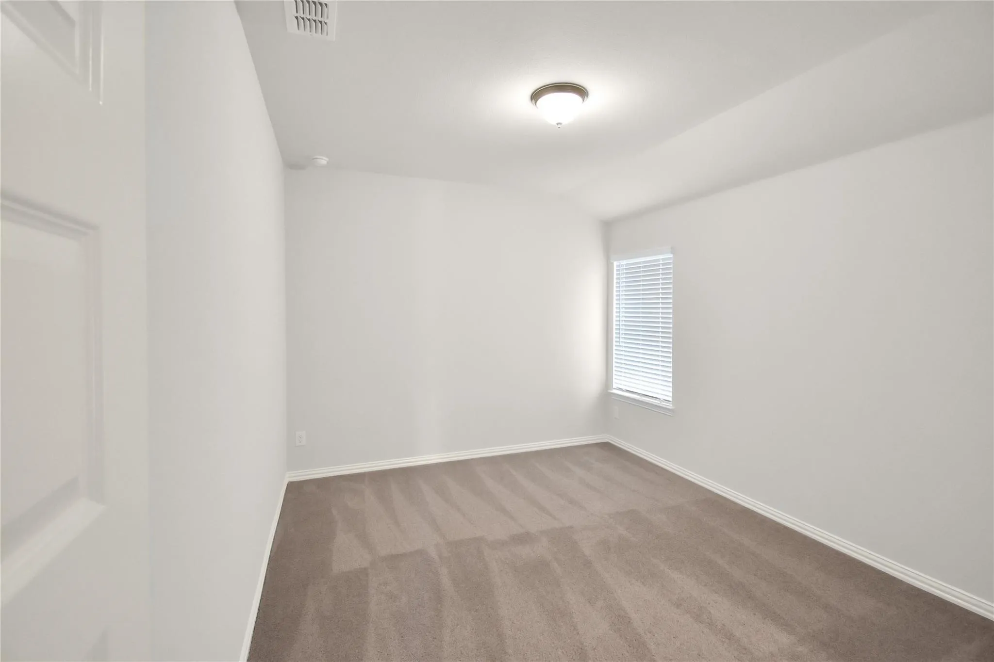 Neutral tone wall paint, carpet flooring, window with blinds, and ceiling-mounted light fixture