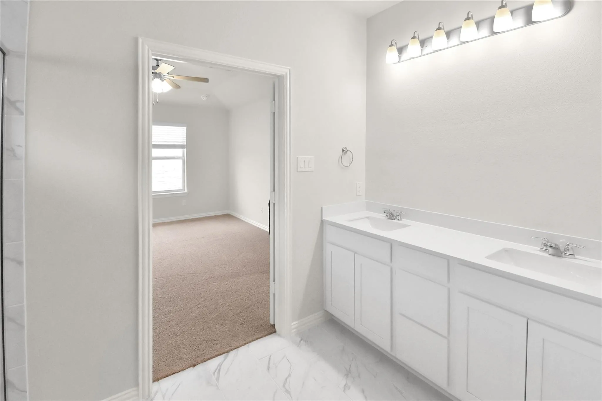 Dual vanity with white cabinetry and integrated sinks, chrome fixtures, and a multi-bulb vanity light fixture