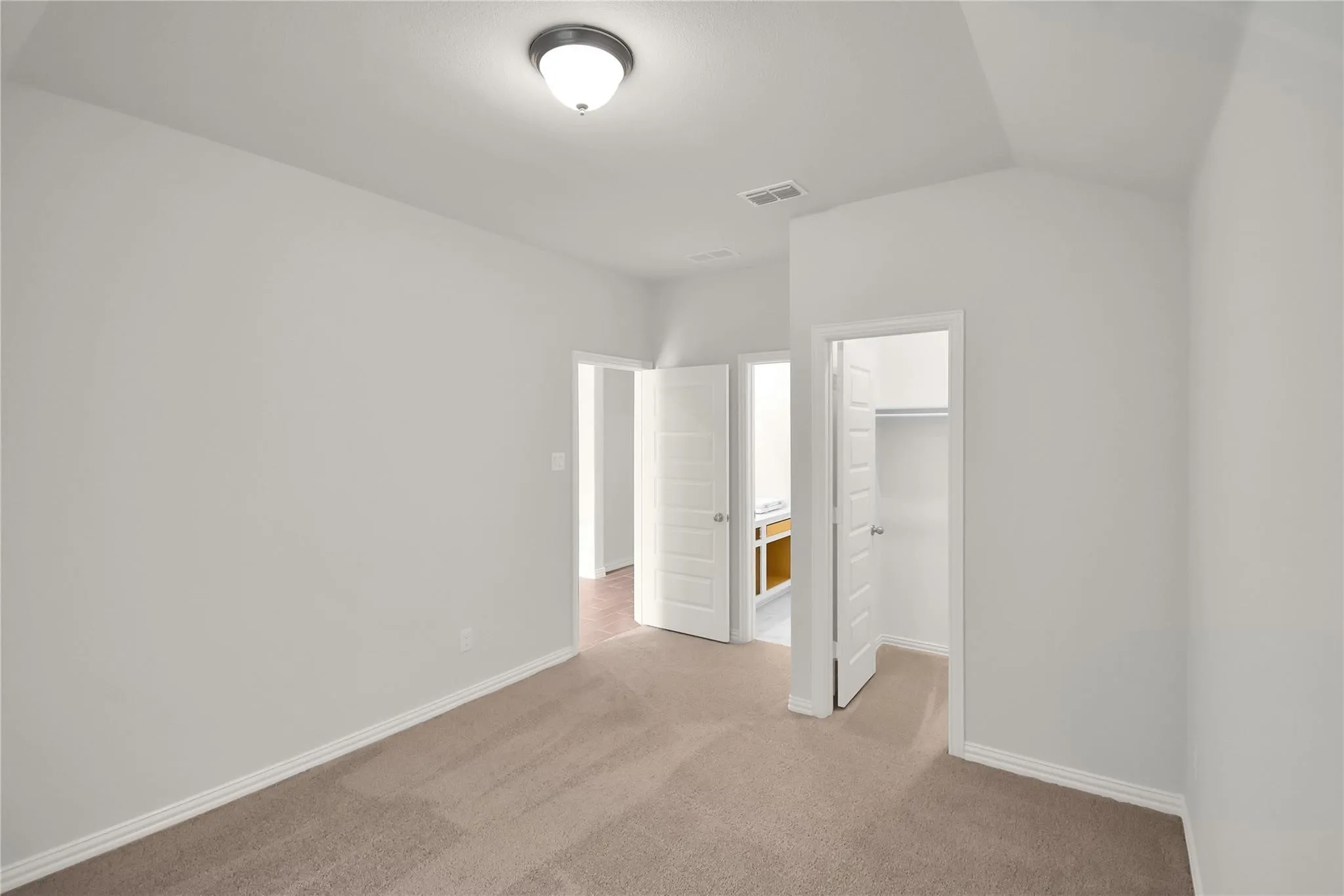 Neutral wall color palette, carpet flooring, flush mount lighting fixture, and a vaulted ceiling