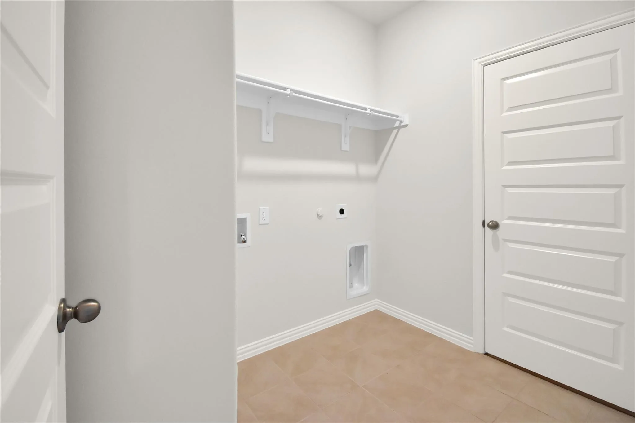 Laundry area featuring tile flooring, white walls, built-in shelving, and panel doors