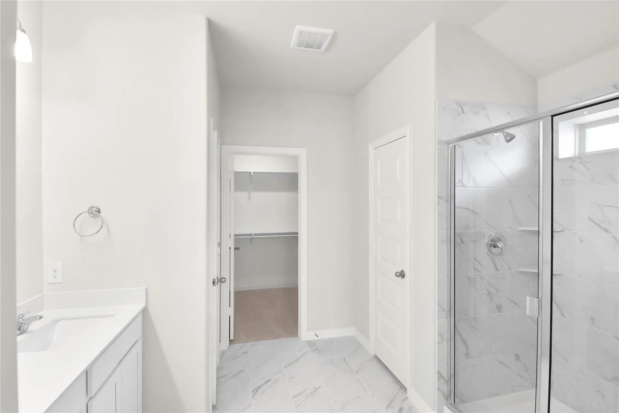 Walk-in shower with clear glass enclosure and stone-look tile surround