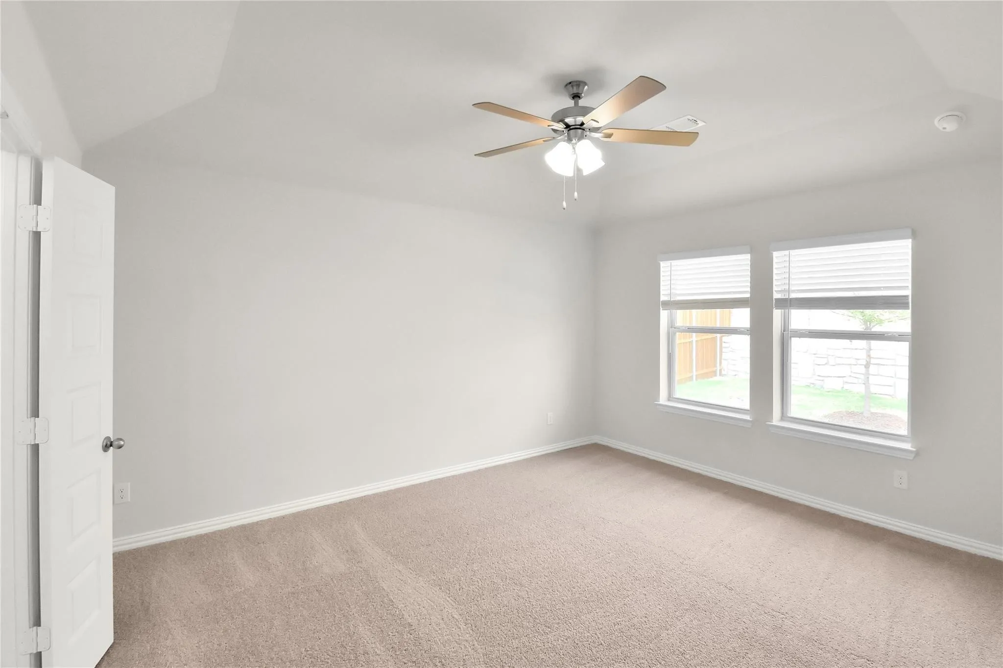 Vaulted ceiling with a ceiling fan, two windows with blinds, and neutral carpet flooring