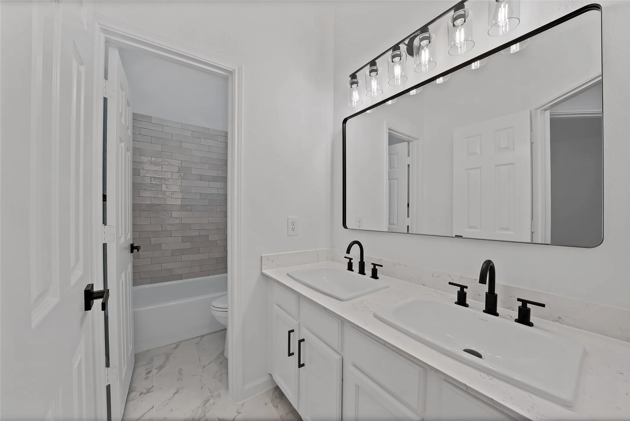 Gorgeous guest bathroom boasts painted cabinetry, hardware, dual sinks, designer mirror, new plumbing fixtures, lighting and tile.