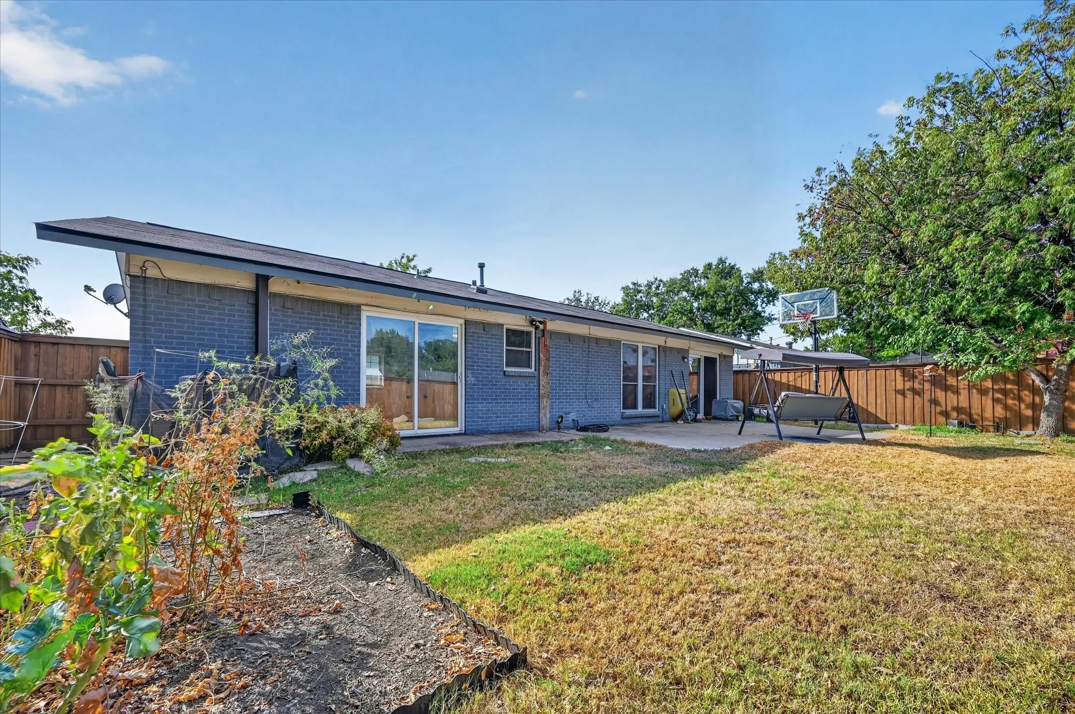 Rear exterior featuring a concrete patio, sliding glass doors, and a brick facade