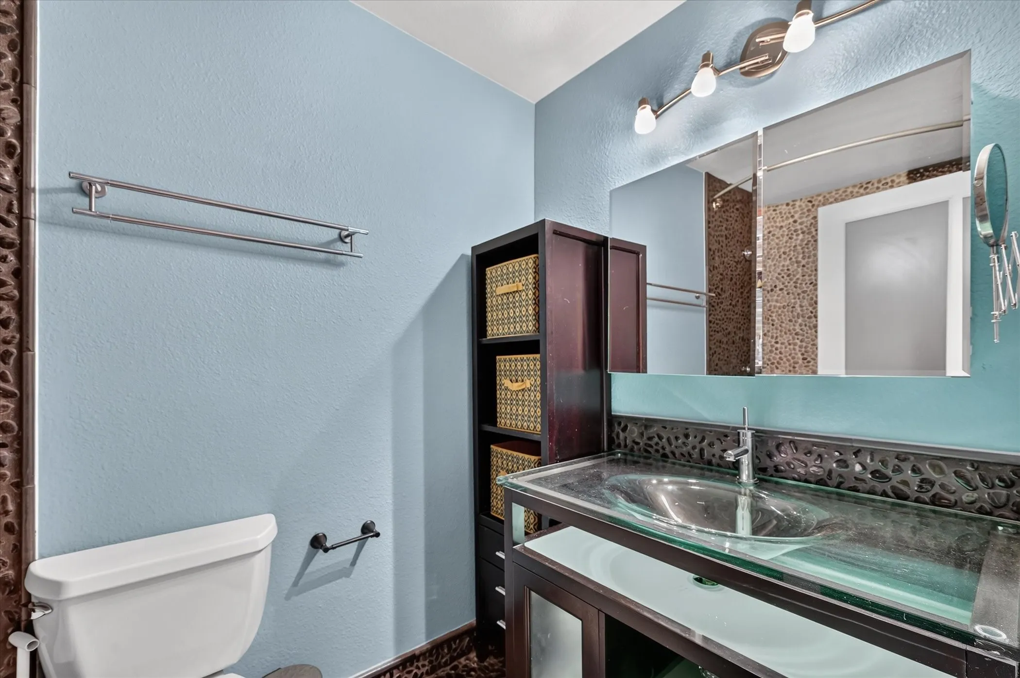 Vessel sink with a glass countertop, wood-finish vanity, and integrated shelving