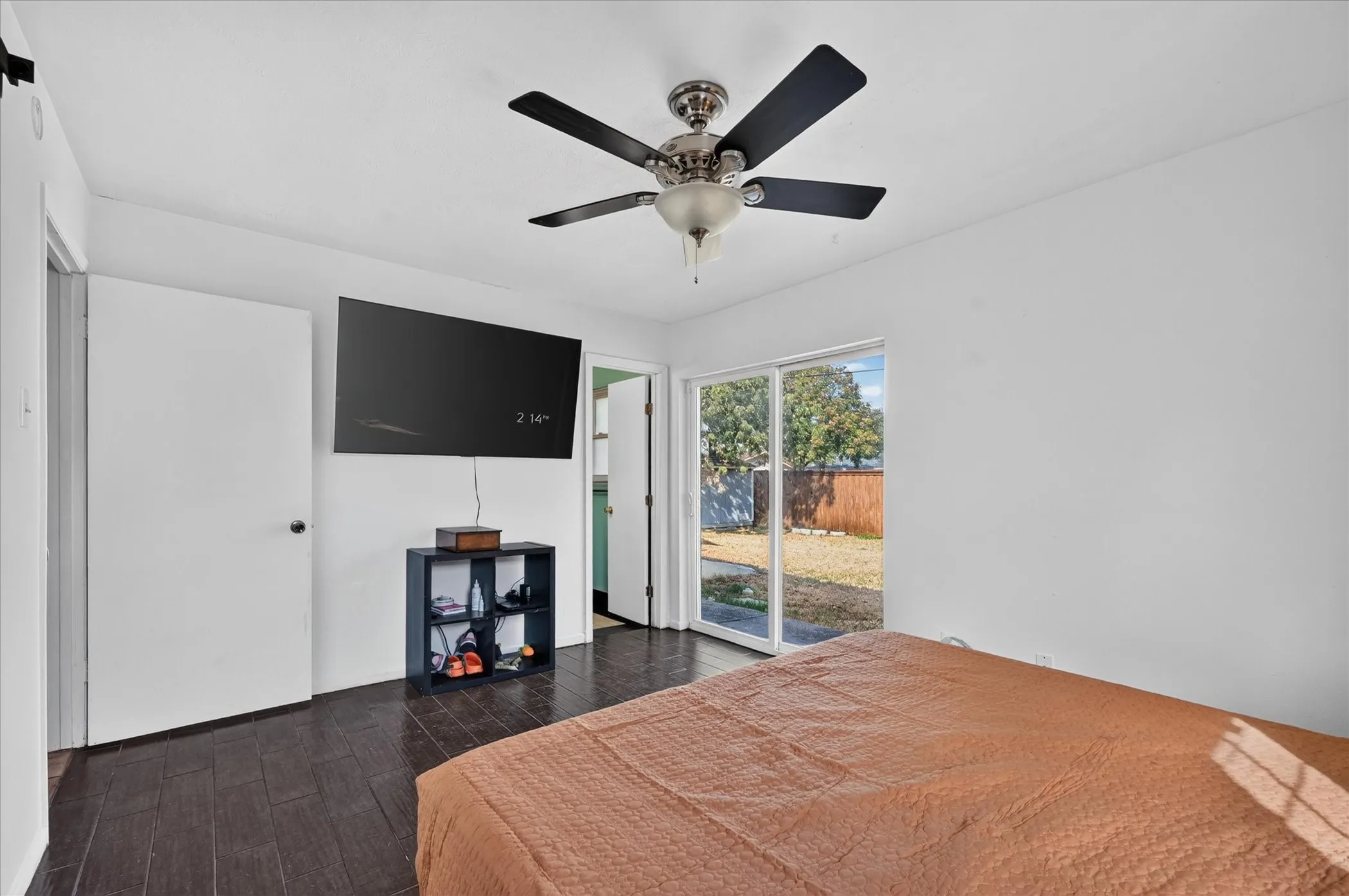 Wood-finish flooring, ceiling fan, white walls, and sliding glass door to exterior