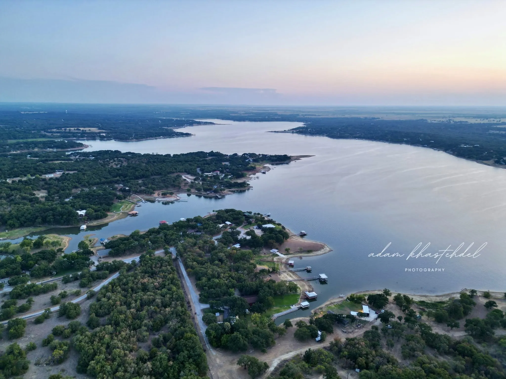 Expansive lake and surrounding wooded shoreline, featuring multiple waterfront properties with private docks
