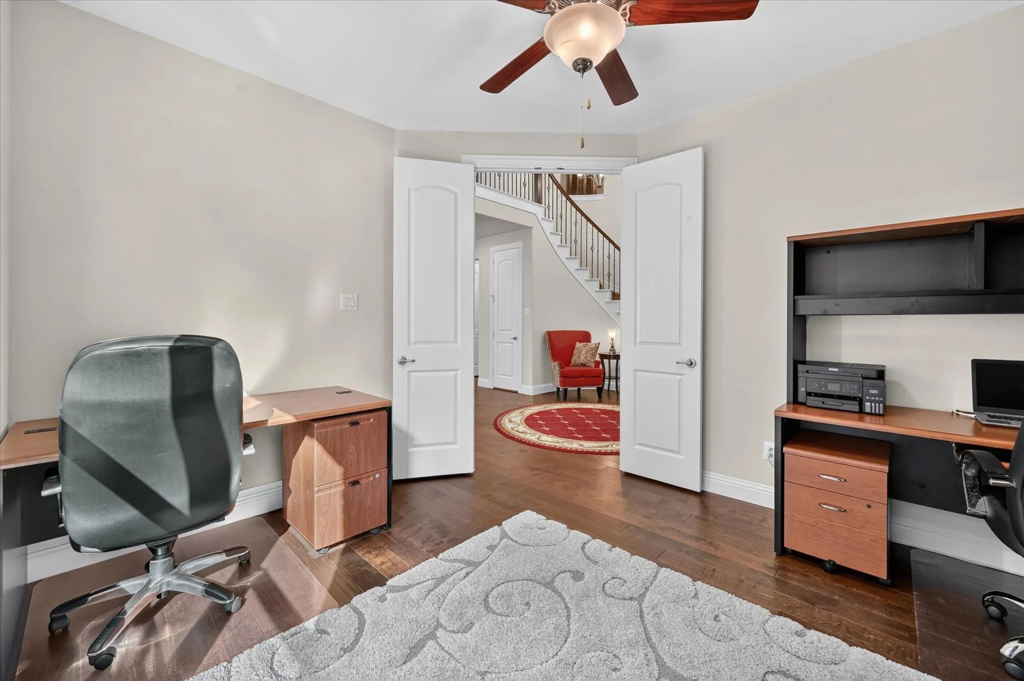 Hardwood flooring, painted walls, ceiling fan with integrated lighting, and white paneled double doors