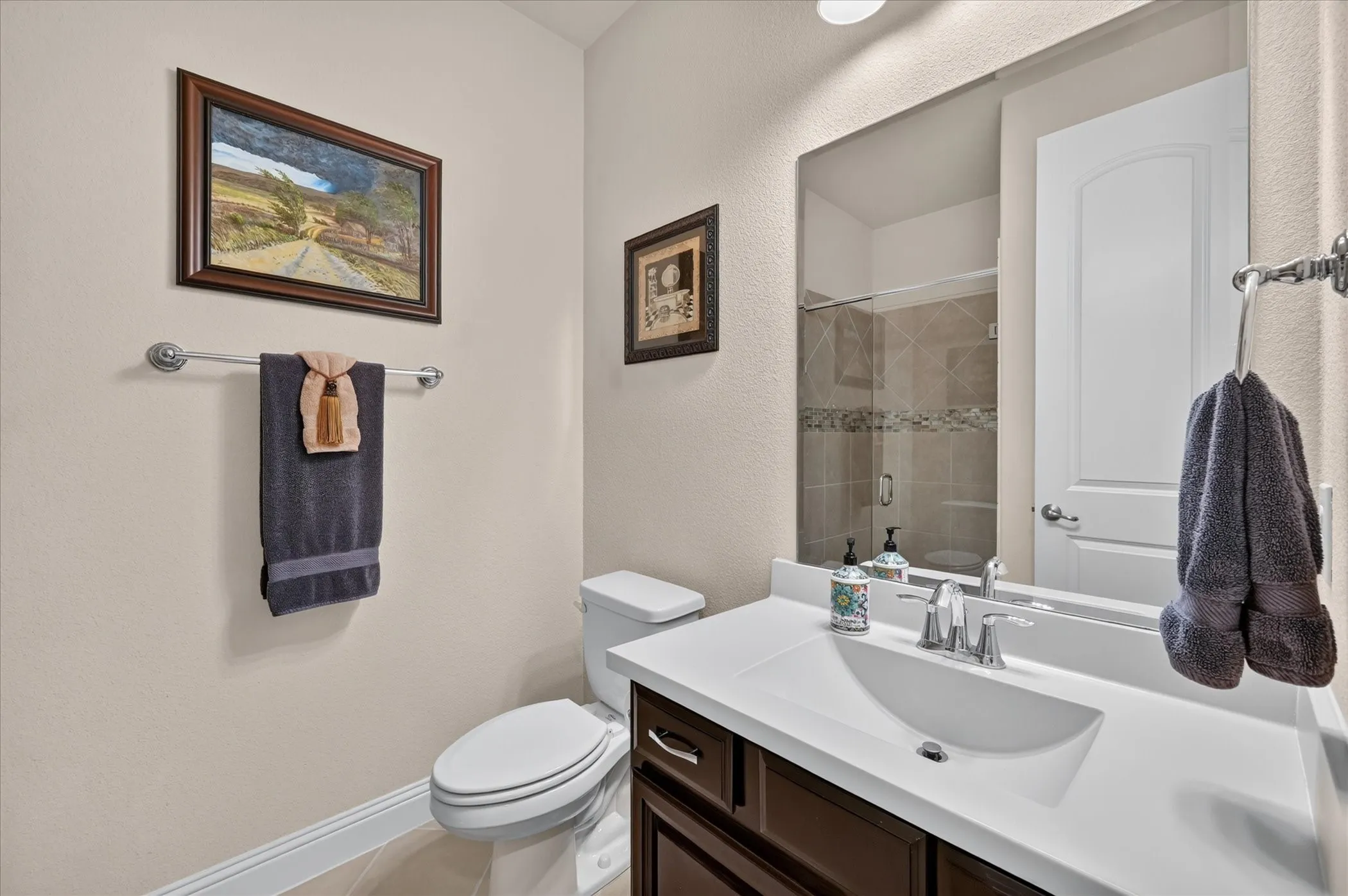 Vanity with an integrated sink, polished chrome faucet, wood-finish cabinetry, and a full-width wall mirror