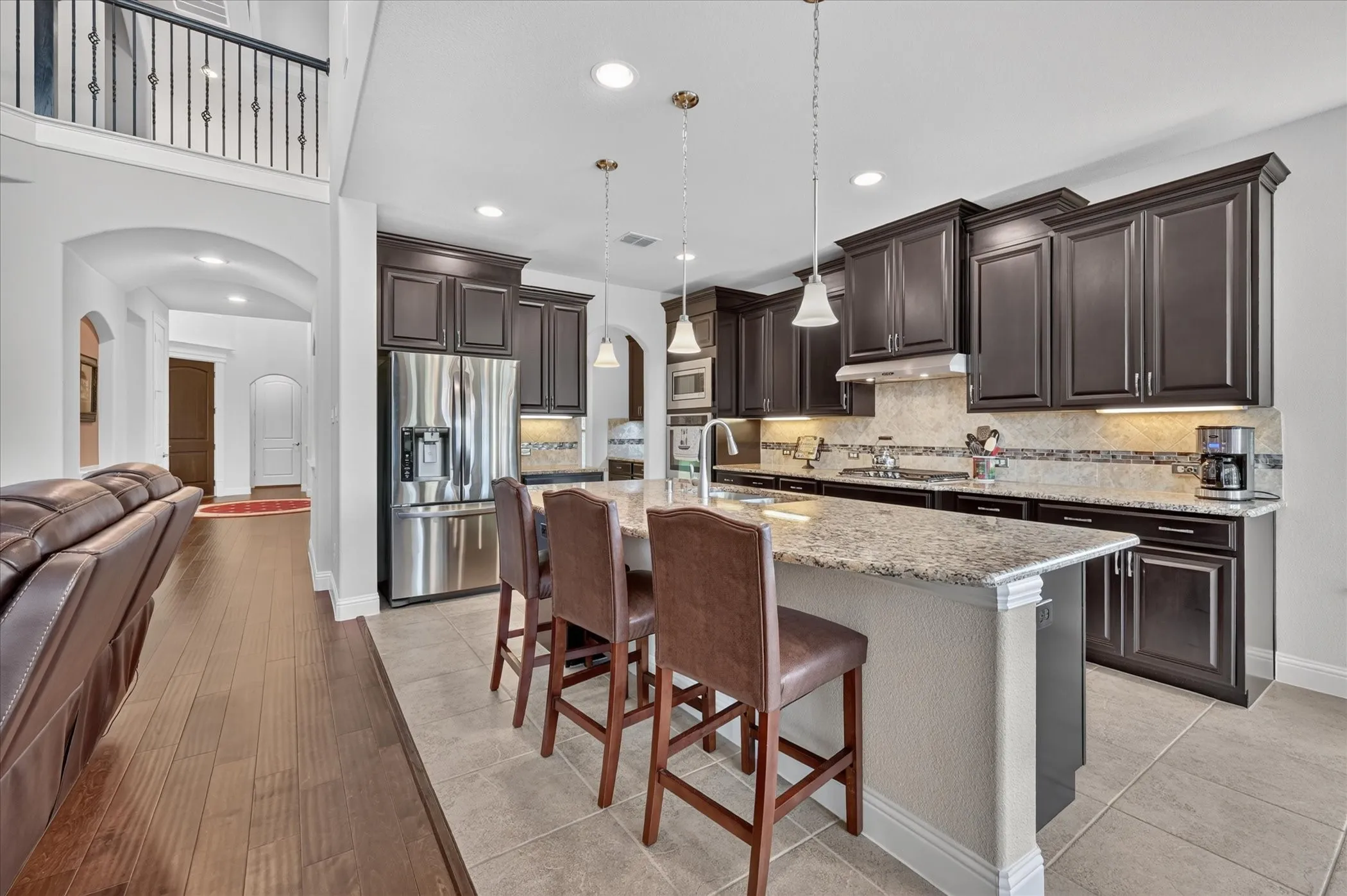 Kitchen featuring dark wood cabinetry, a large kitchen island with a light-toned countertop, stainless steel appliances, and tile flooring