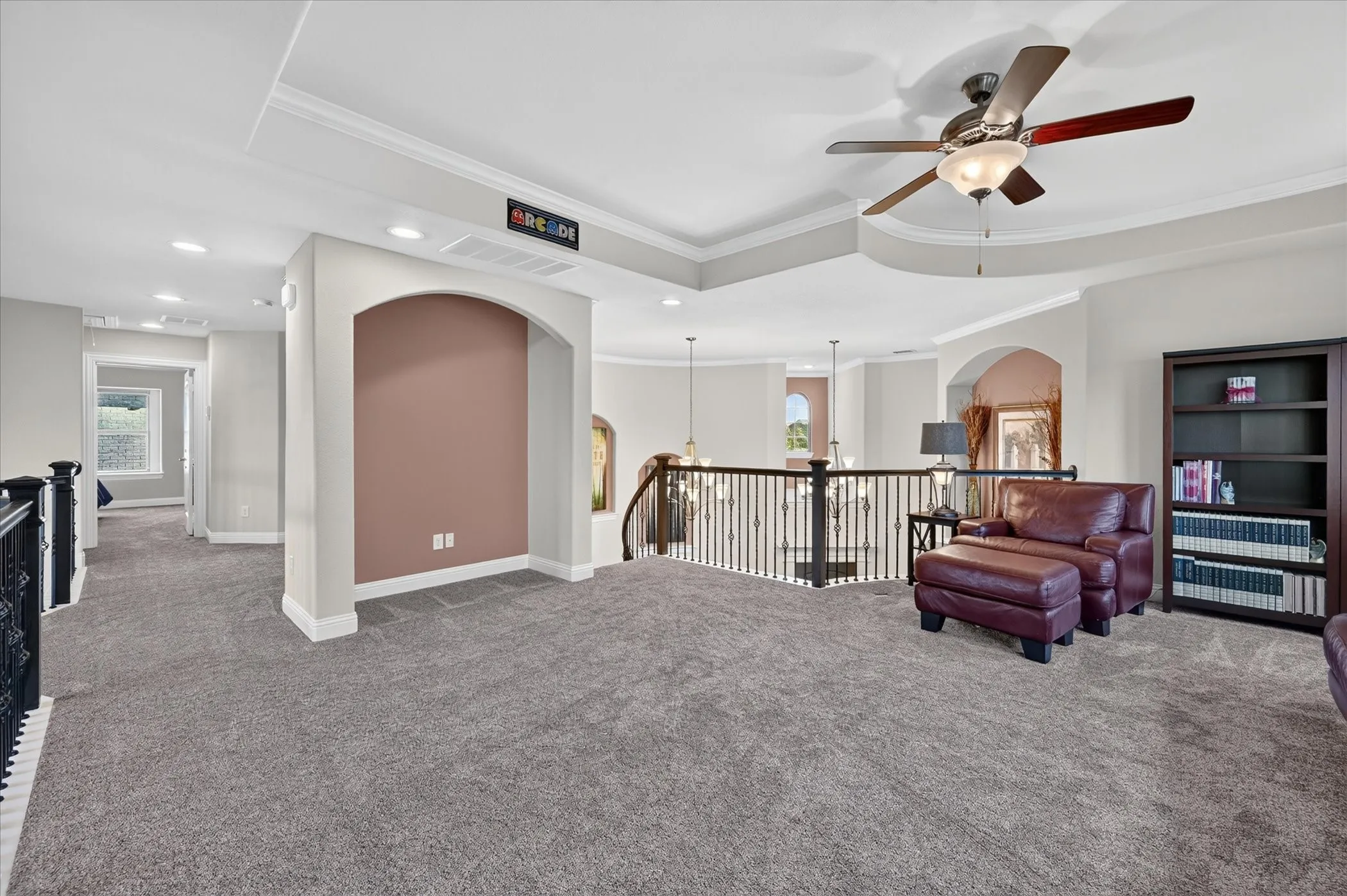 Carpeted loft area featuring a ceiling fan with light, recessed lighting, and an arched niche