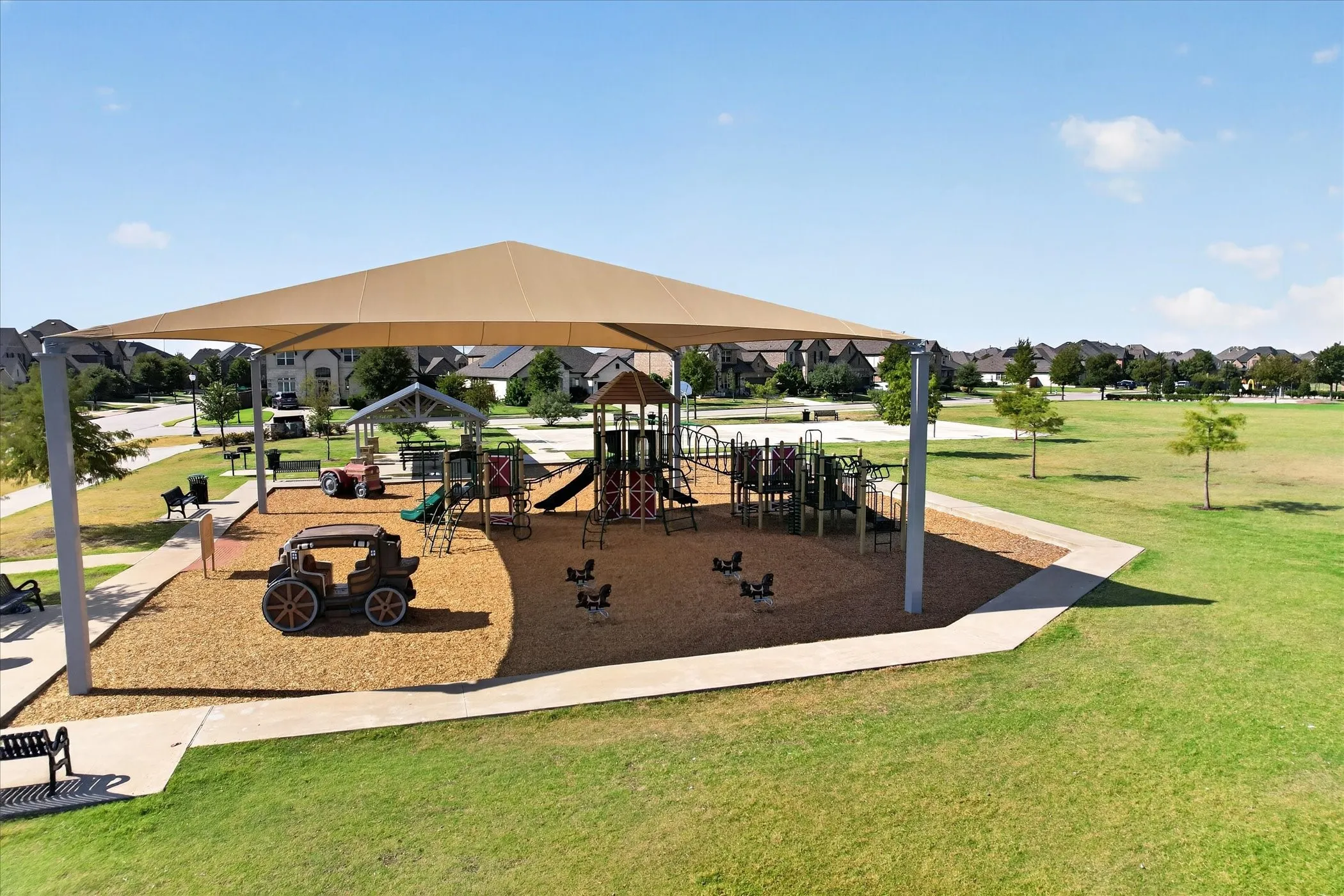 Playground featuring a large shade structure, multiple play structures, and a wood chip surface