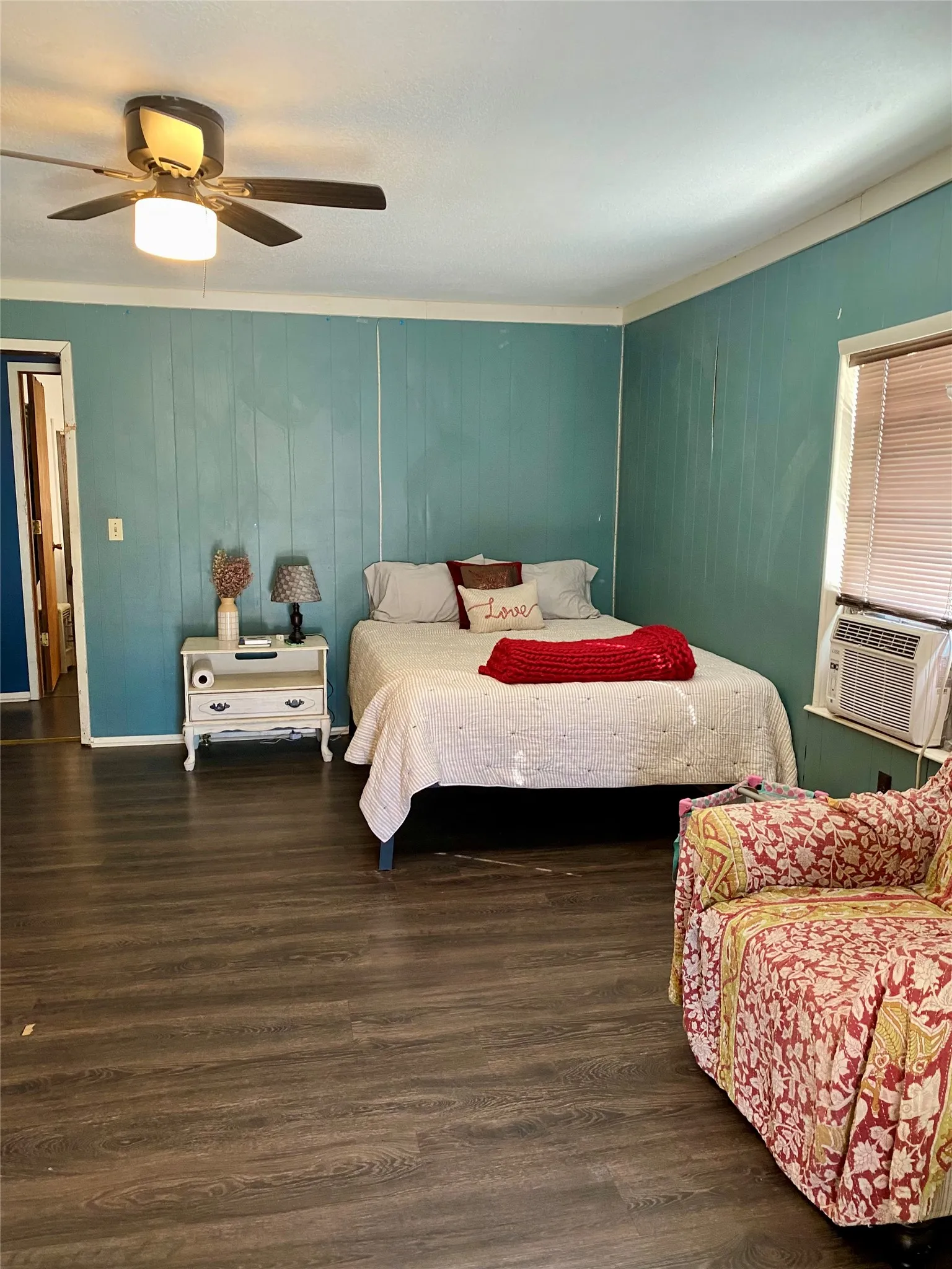 Bedroom with a ceiling fan, a wainscoted wall, a textured ceiling, and wood finished floors