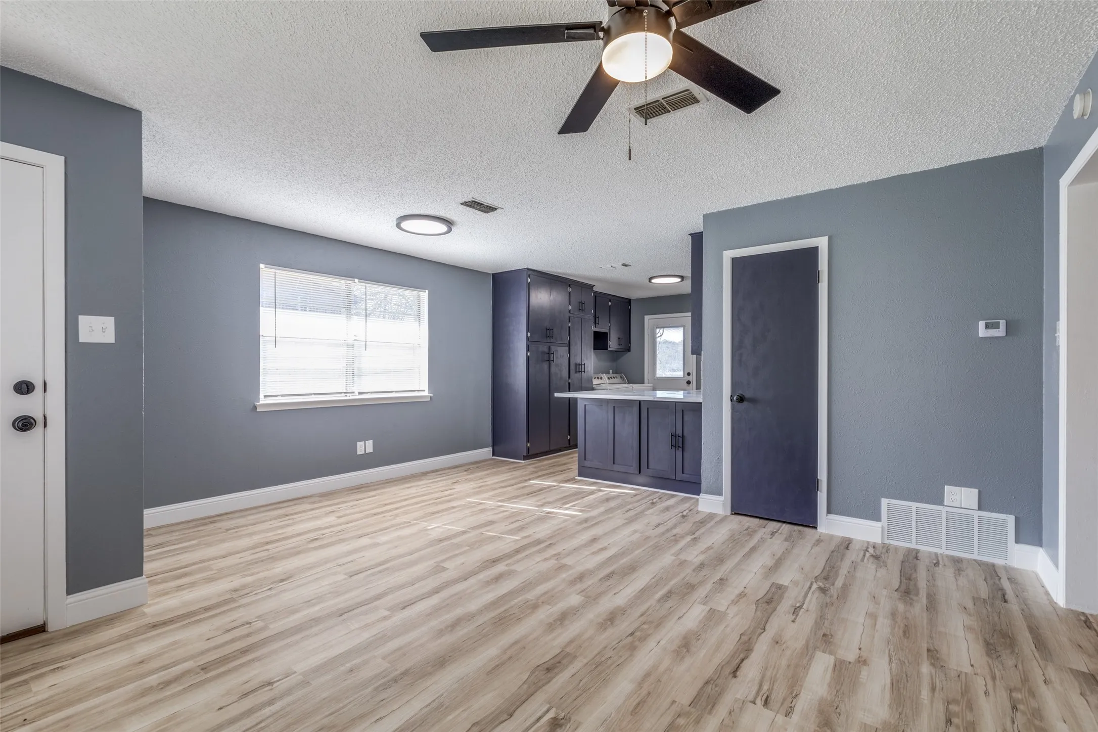 Open-concept living area with wood-finish flooring, a ceiling fan, and recessed lighting