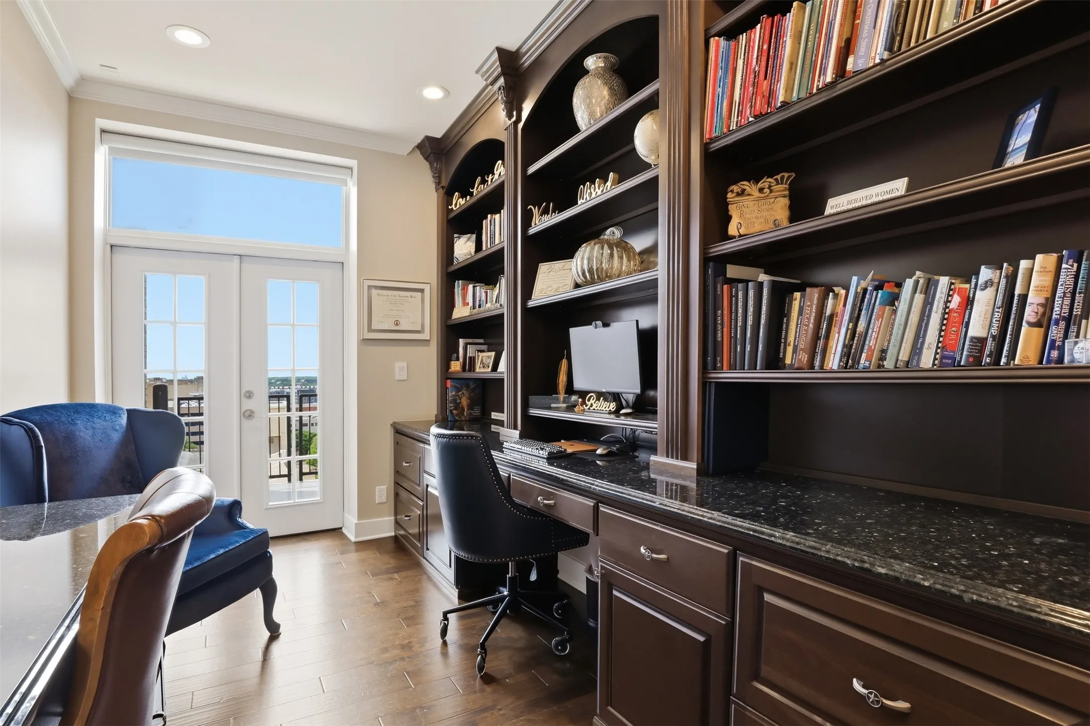 Built-in shelving with integrated desk, dark wood-finish cabinetry, and speckled dark countertops