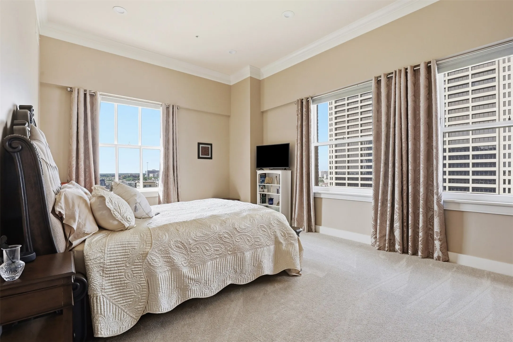 Spacious room featuring multiple windows, neutral wall tones, crown molding, recessed lighting, and light-toned carpeting