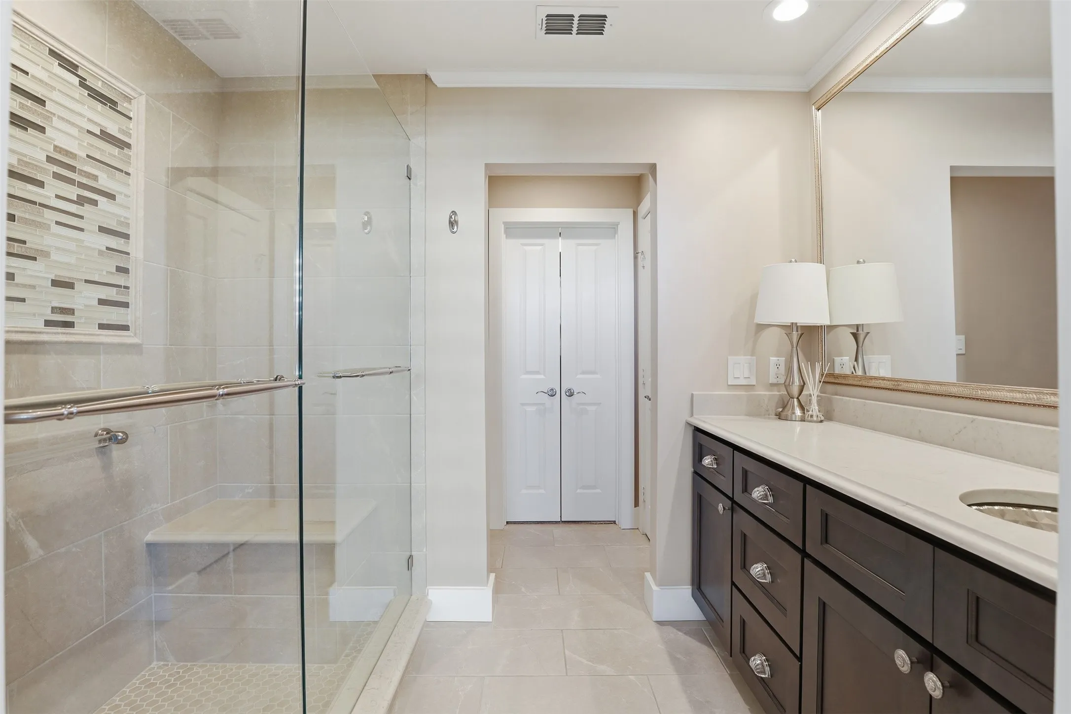 Walk-in shower with a built-in bench, glass enclosure, and decorative tile accent