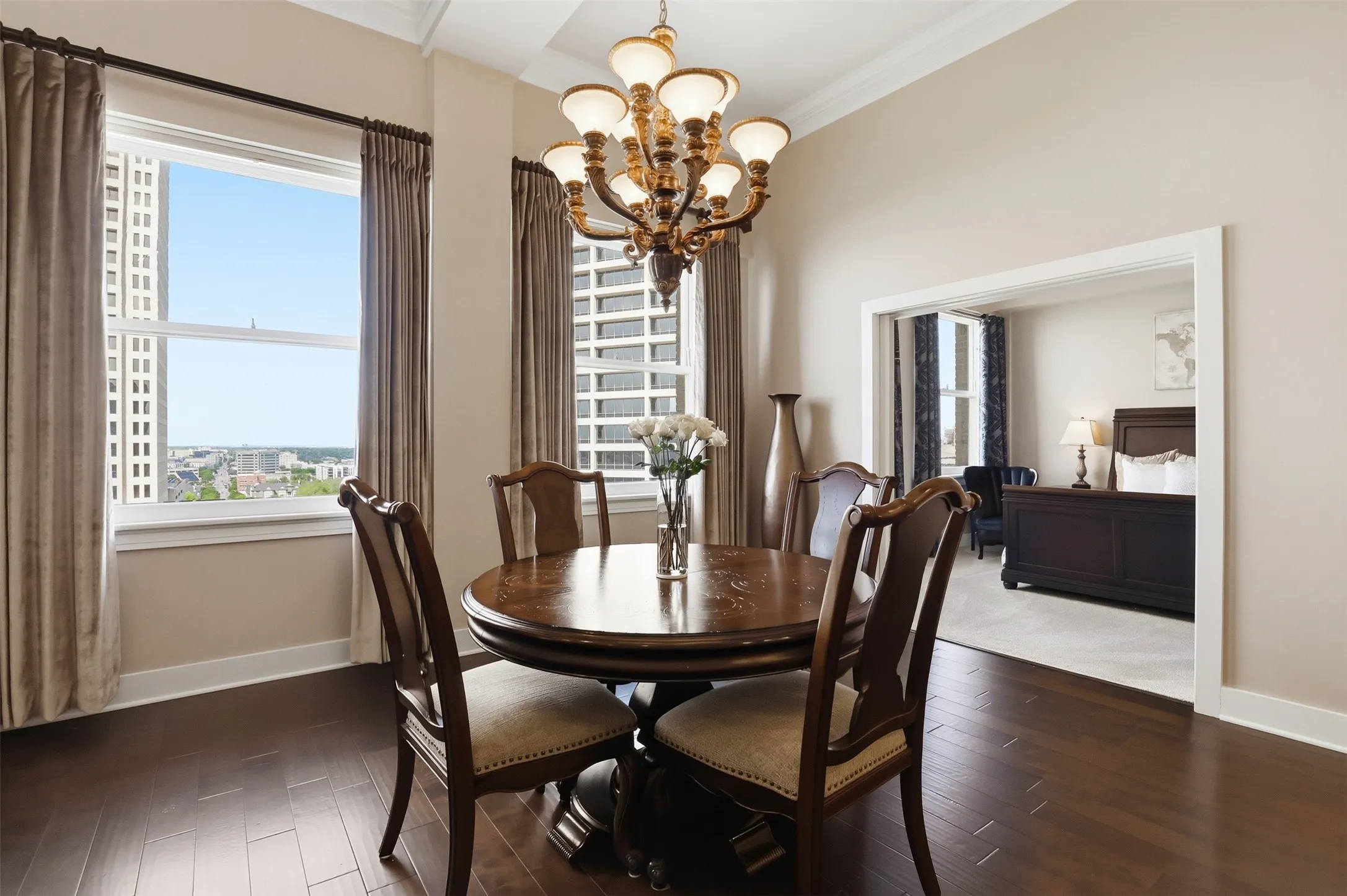 Recessed ceiling with an ornate chandelier, wood-finish flooring, and expansive windows