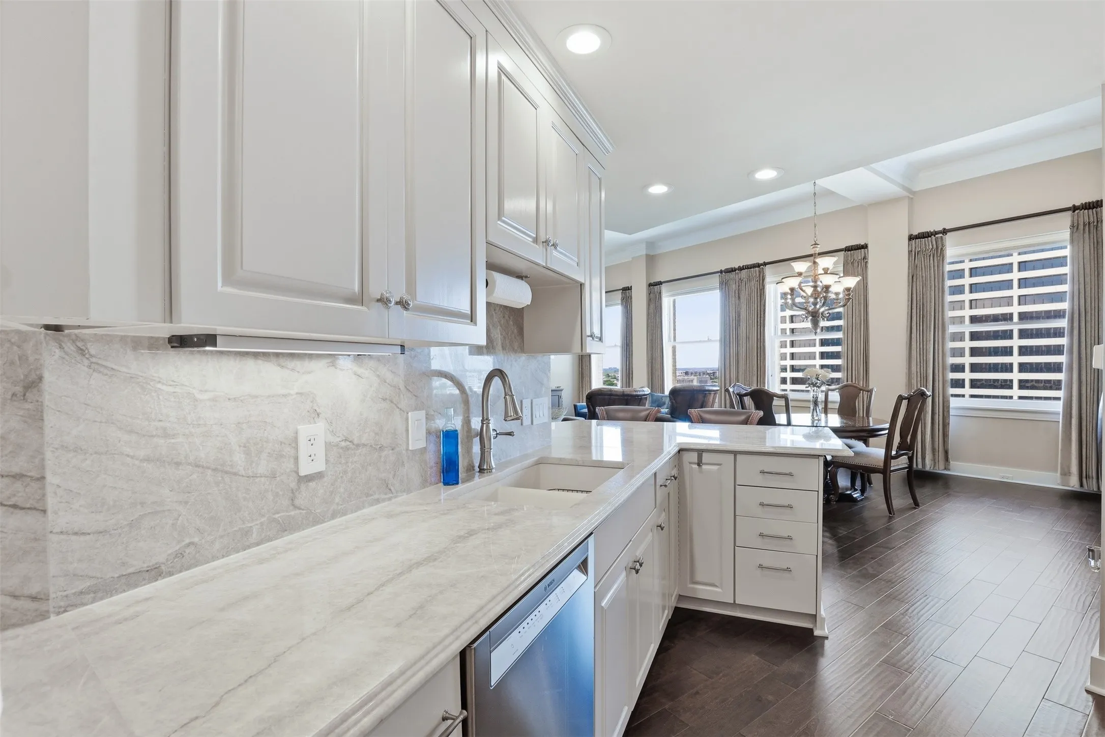 Contemporary kitchen featuring white cabinetry with chrome hardware, marble subway tile backsplash, light wood-finish countertops, and stainless steel appliances including a built-in dishwasher