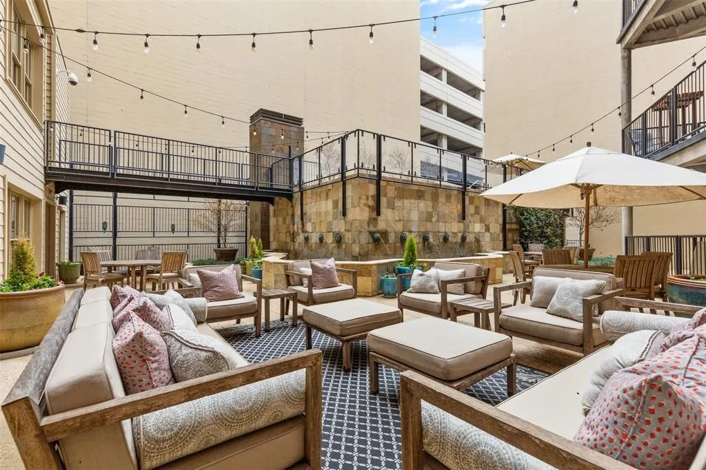 Outdoor courtyard with string lighting, a stone water feature, and a raised metal walkway