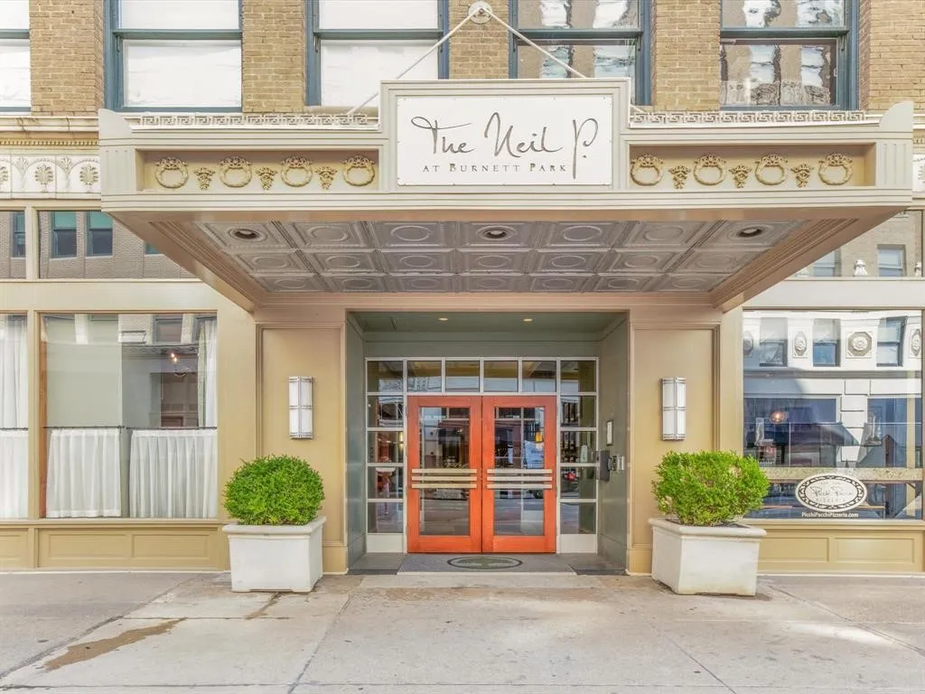 Covered entrance featuring a decorative ceiling, double-door entry, brick building facade, and ground-level storefront windows