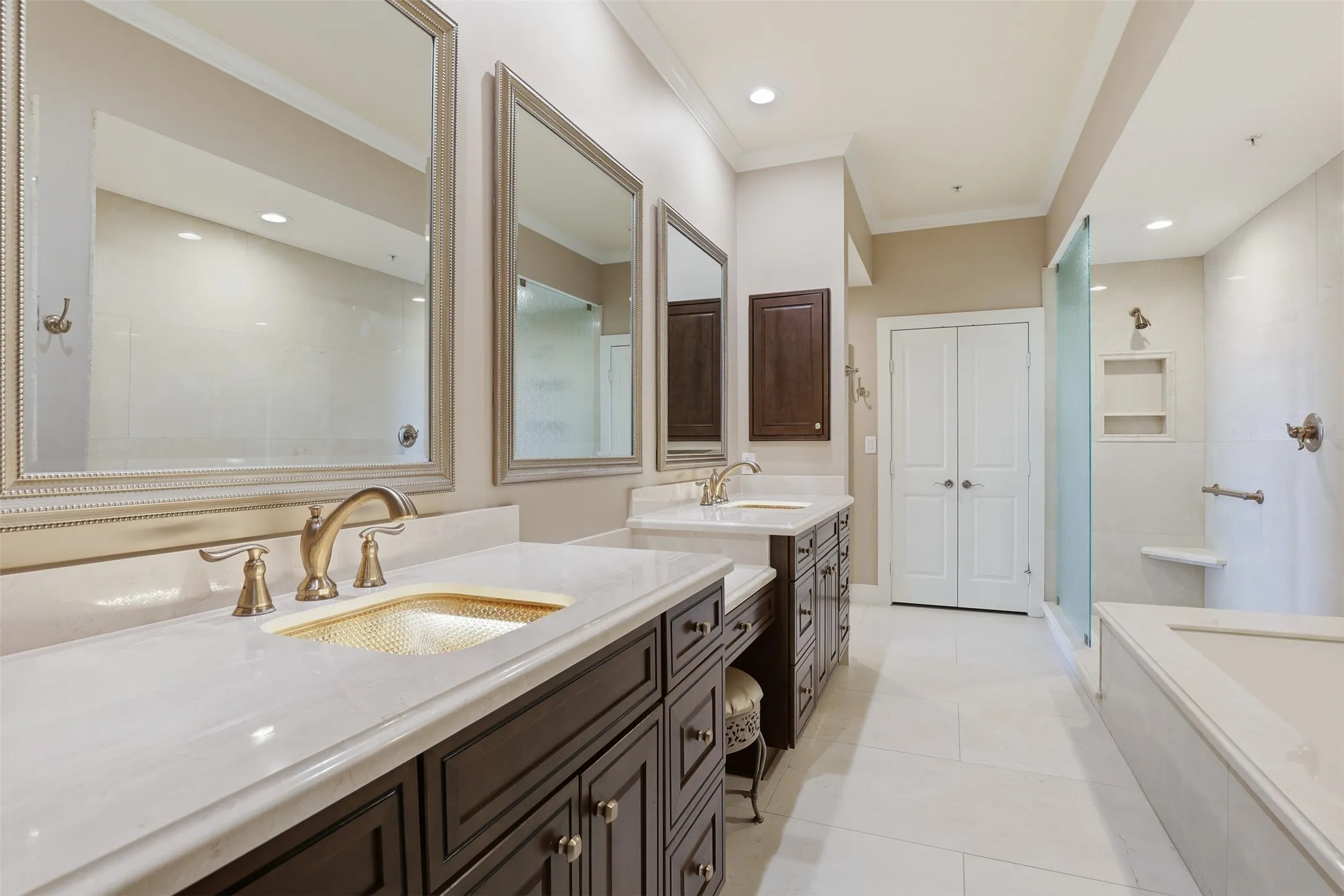 Dual vanity with dark wood cabinetry, white countertops, and bronze-finish fixtures