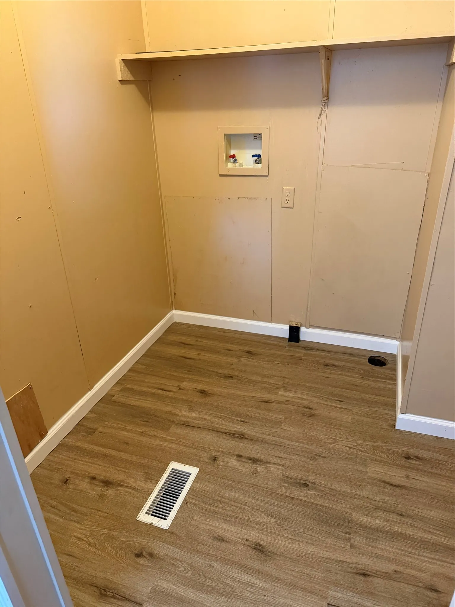 Utility space featuring wood-finish flooring, a wall-mounted shelf, and a washing machine hookup
